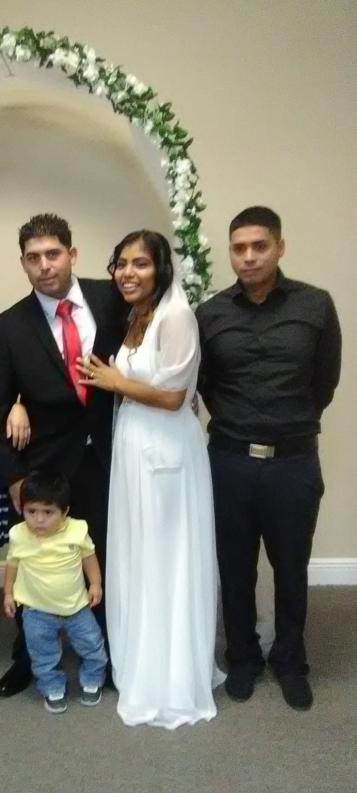 A couple shares a joyful moment at their wedding with family by their side, dressed formally.