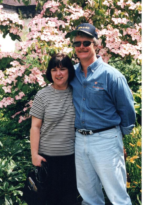 A man and woman standing in front of a flowering tree