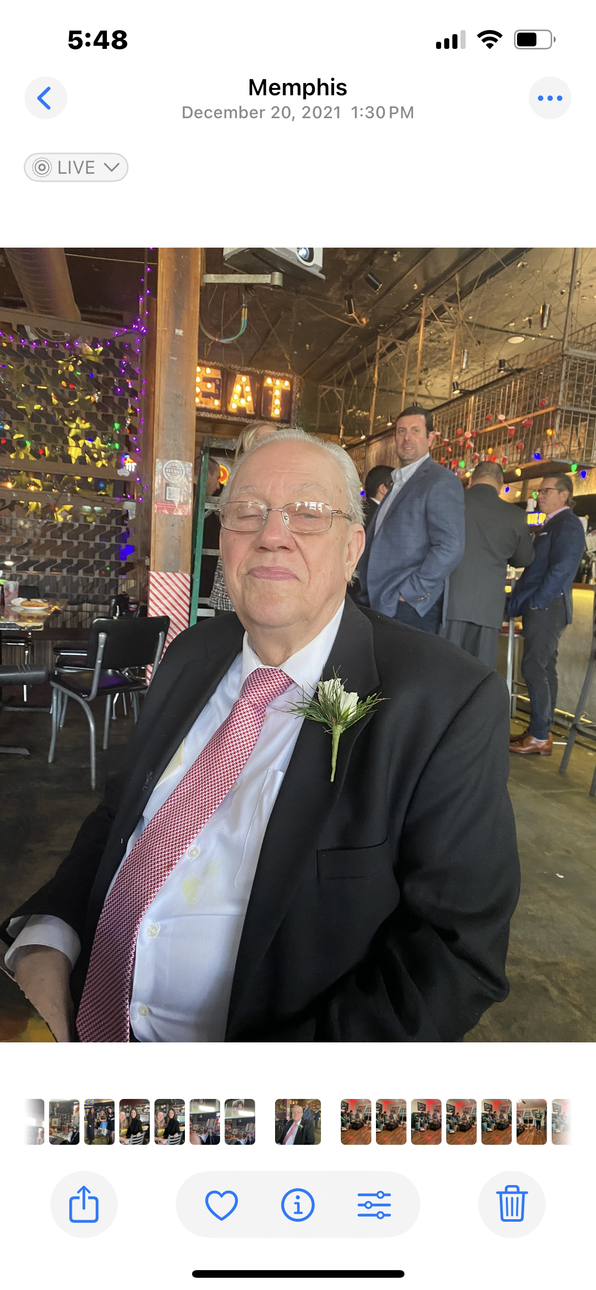 A gentleman in a suit smiles while seated at a lively celebration in Memphis during the afternoon.