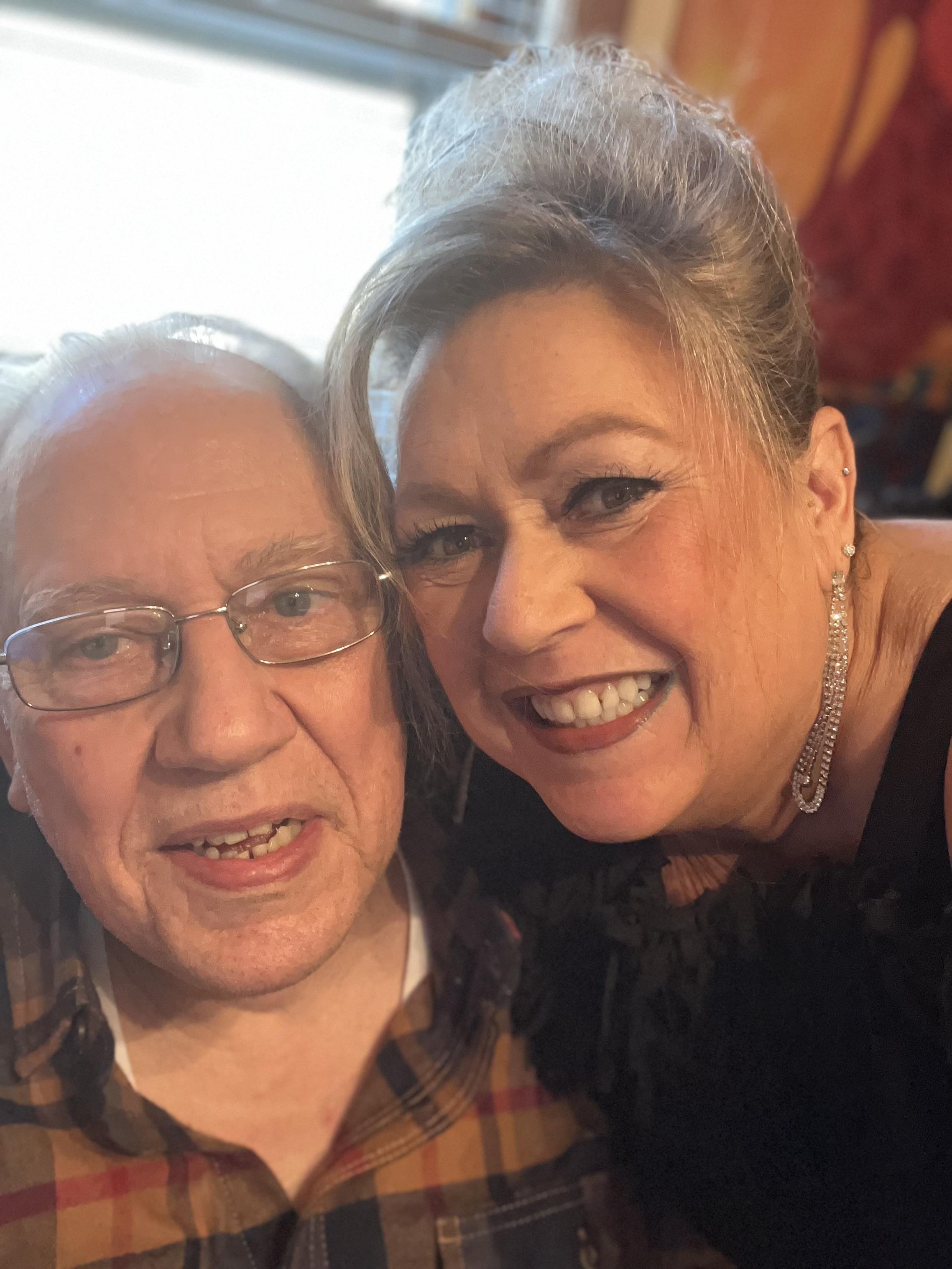 Two friends share a joyful smile while sitting closely in a warm, inviting room.