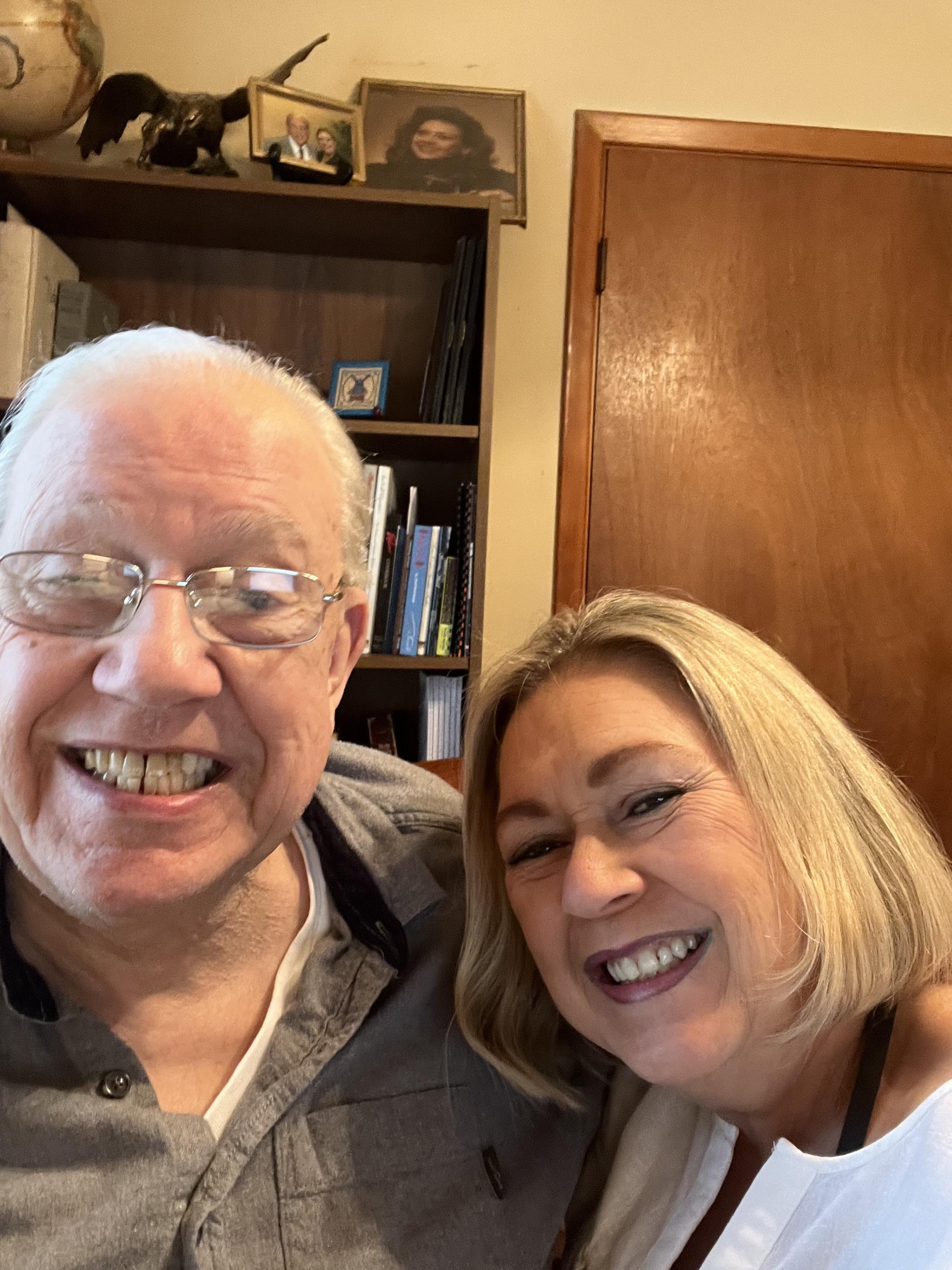 Elderly man and woman share a joyful moment taking a selfie, showcasing bright smiles.