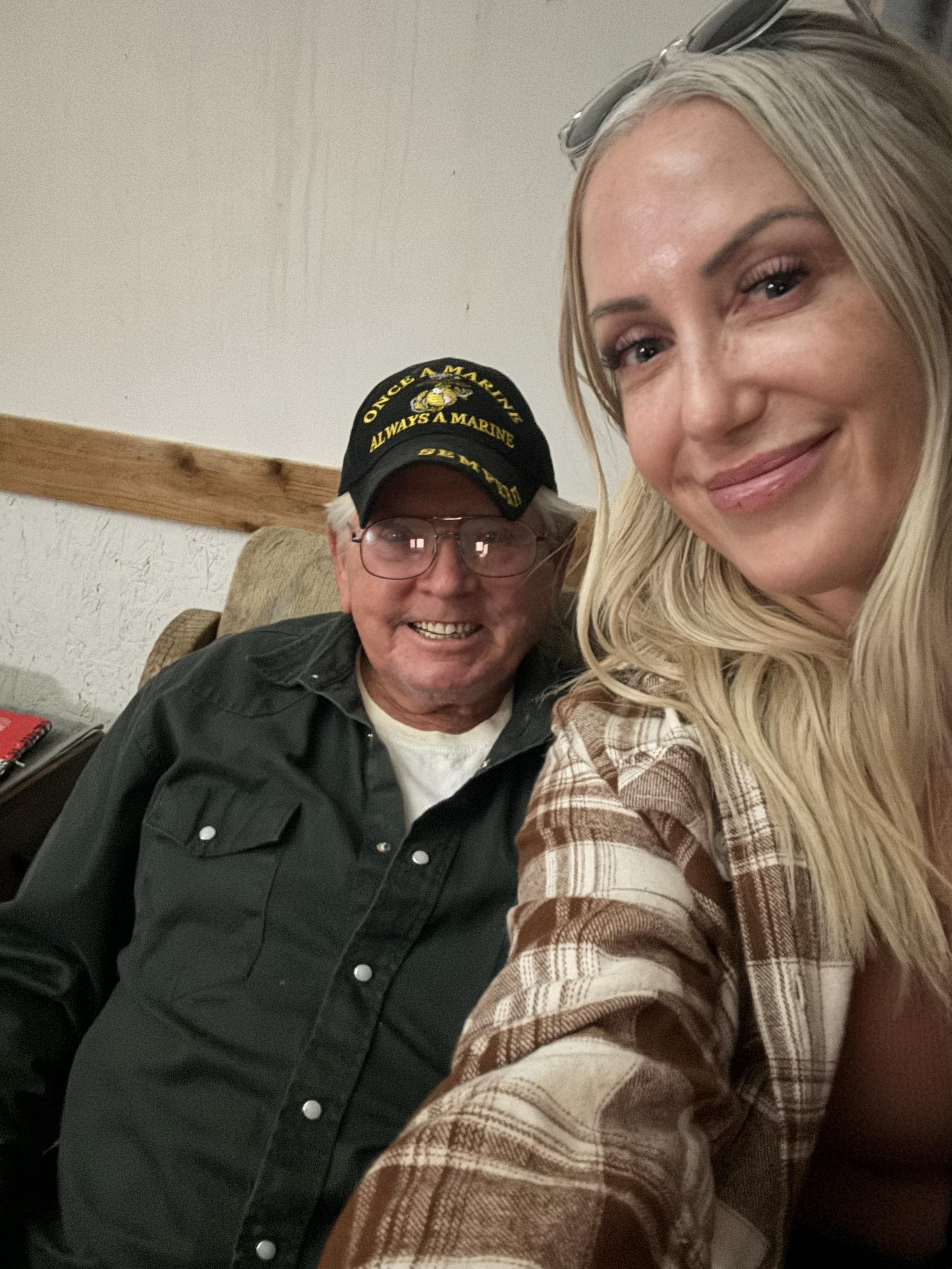 Two friends smile happily while sitting together in a cozy home setting during the evening.