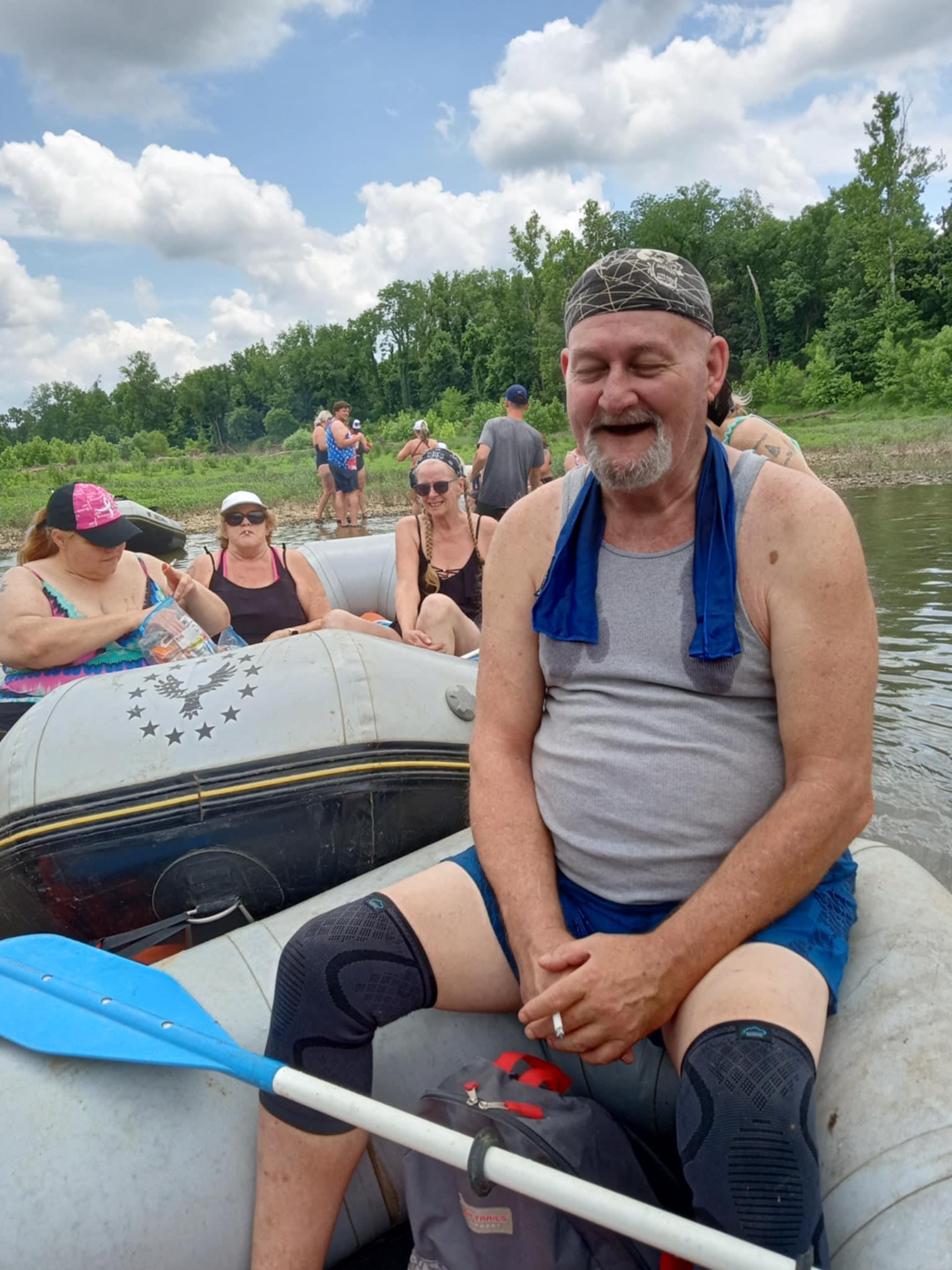 Friends are relaxing on an inflatable raft in a river, enjoying a sunny day and laughter.