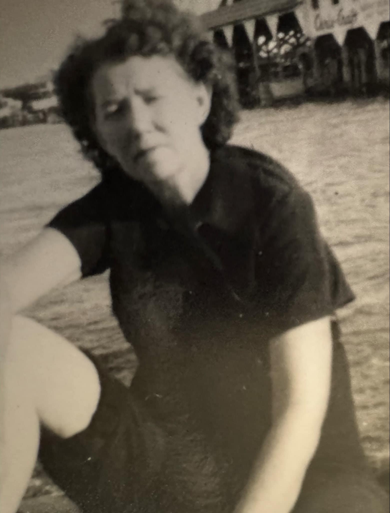 A woman enjoys a sunny day by the water in a casual summer outfit.