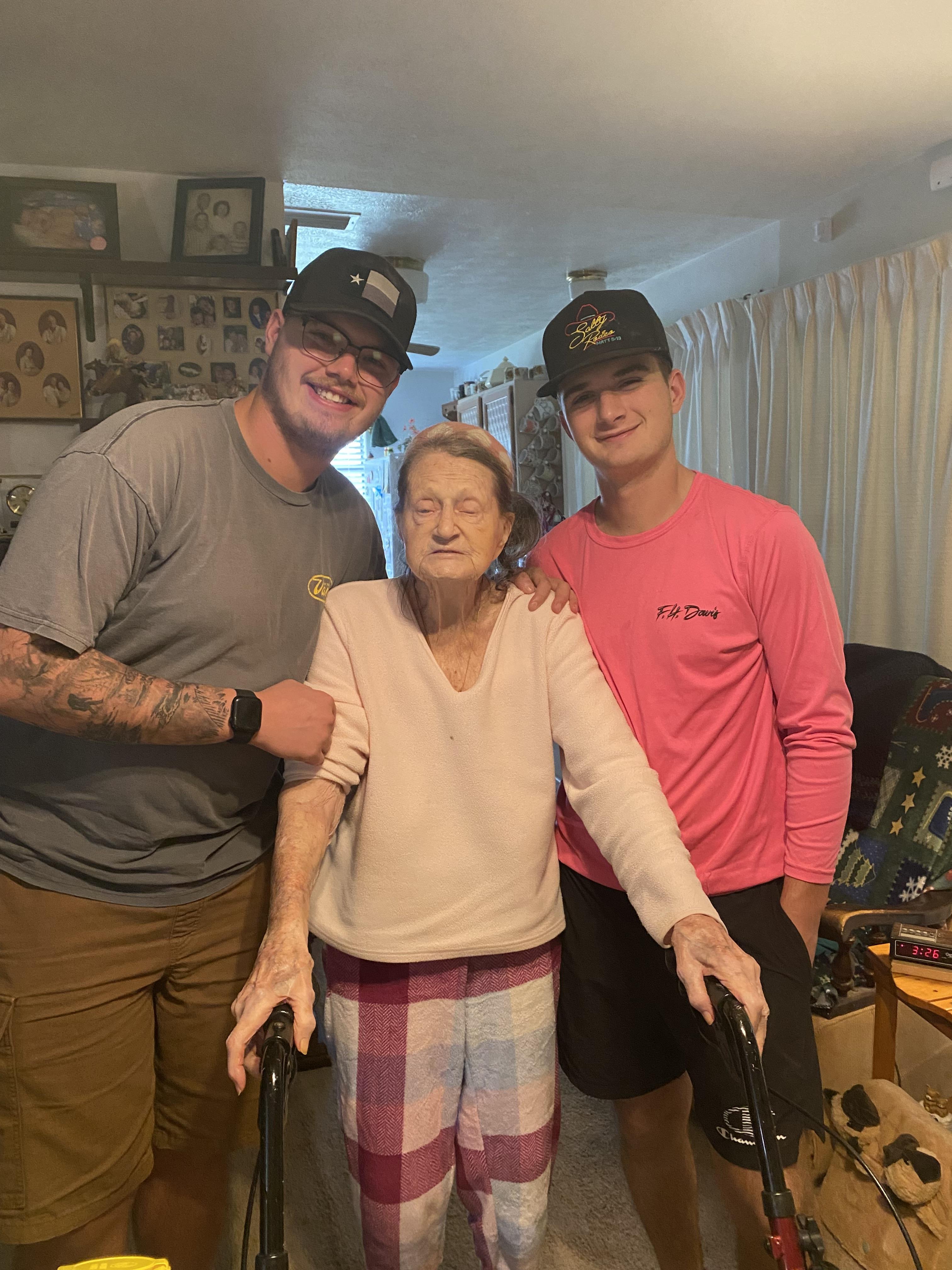 Young men visit an elderly woman at home, offering warmth and companionship.