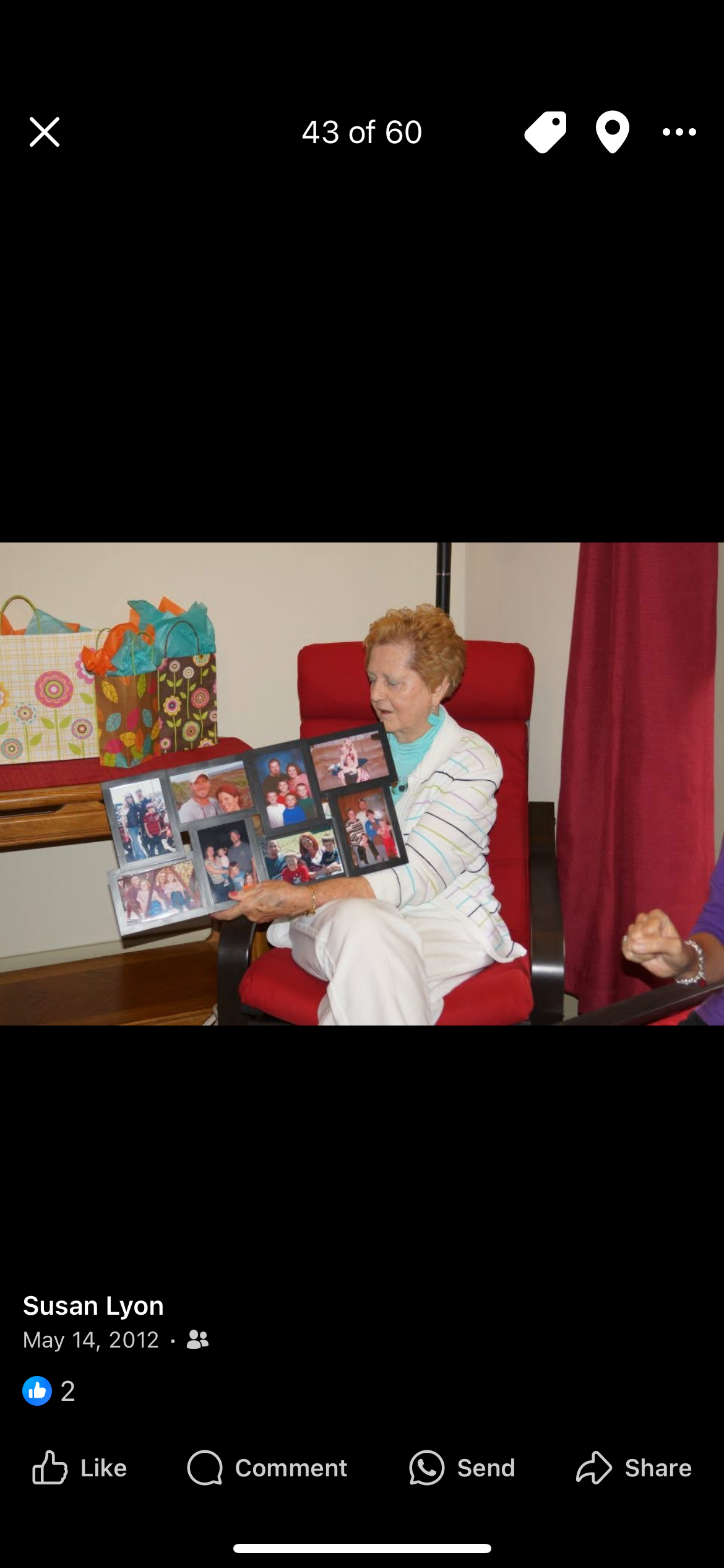 A woman highlights memories from a scrapbook during a family gathering in a living room.