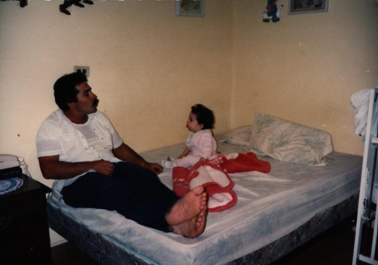 In a cozy room, a father and daughter share a quiet moment on a bed, creating a bond of affection.