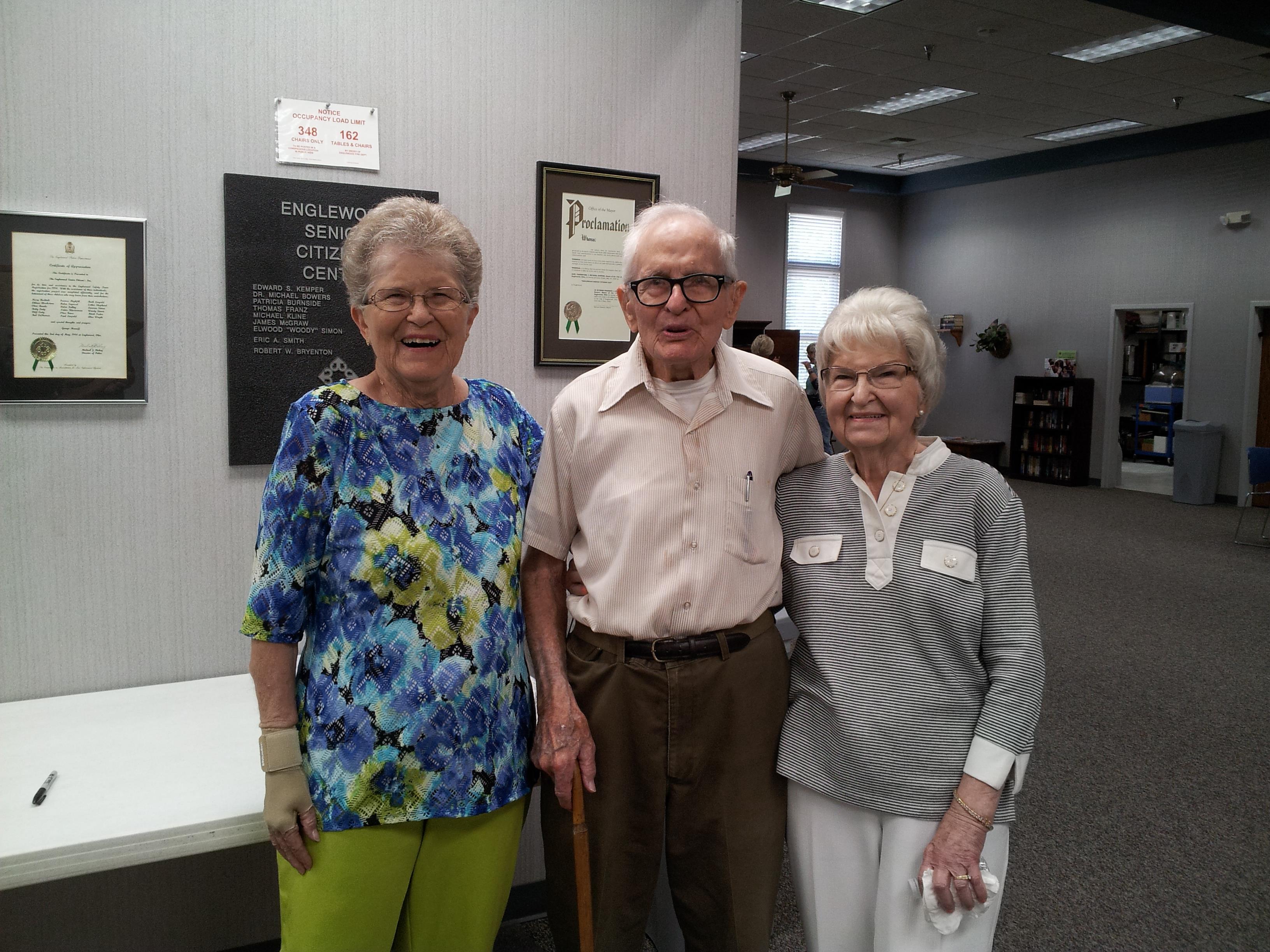 Three elderly individuals enjoy a cheerful moment at a local community center in the afternoon.