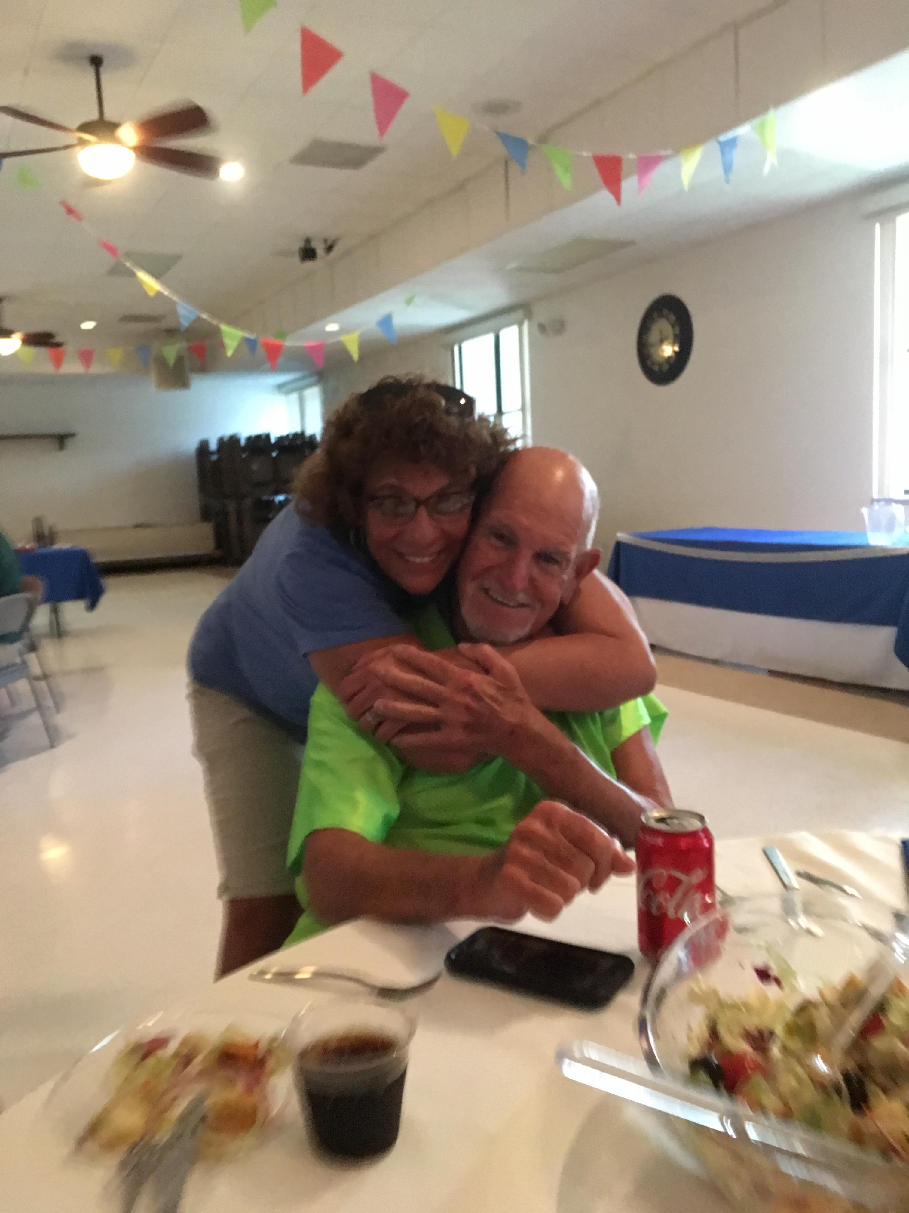 Two friends share a heartfelt moment, embracing and enjoying their time at a festive gathering.