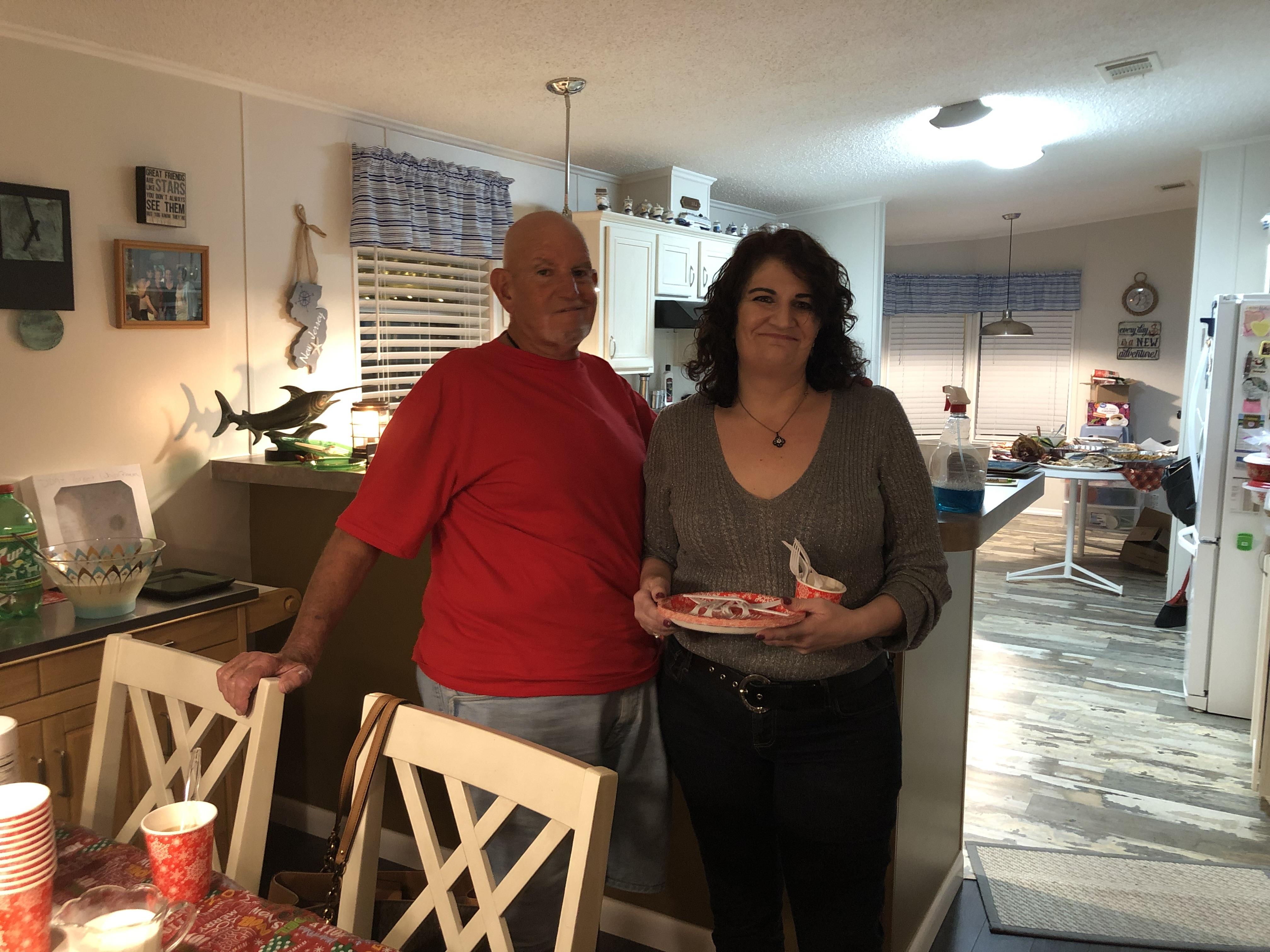 Two friends smile while celebrating together at a cozy home, sharing food and laughter.