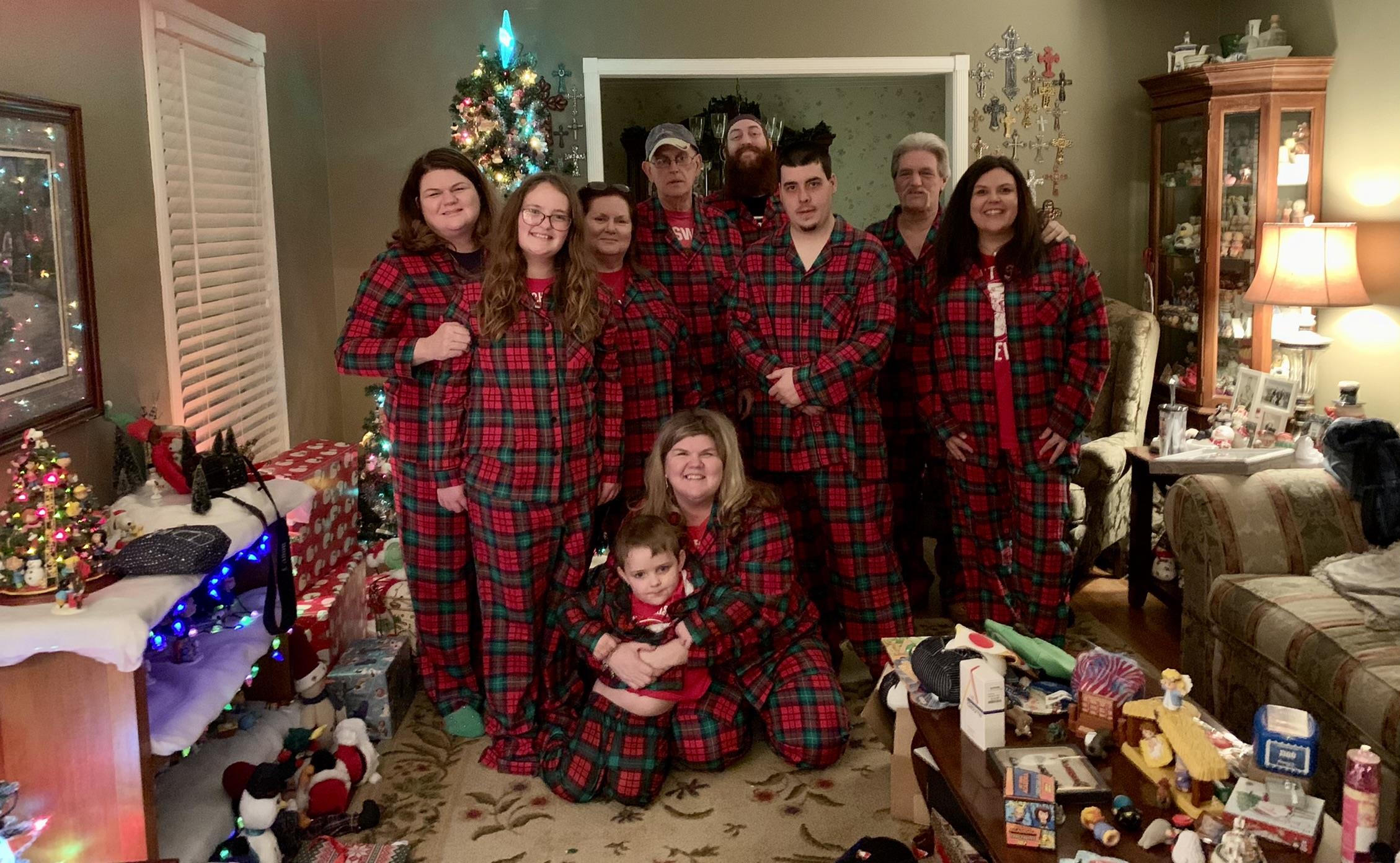 Family members celebrate in matching plaid pajamas, surrounded by decorations and gifts.