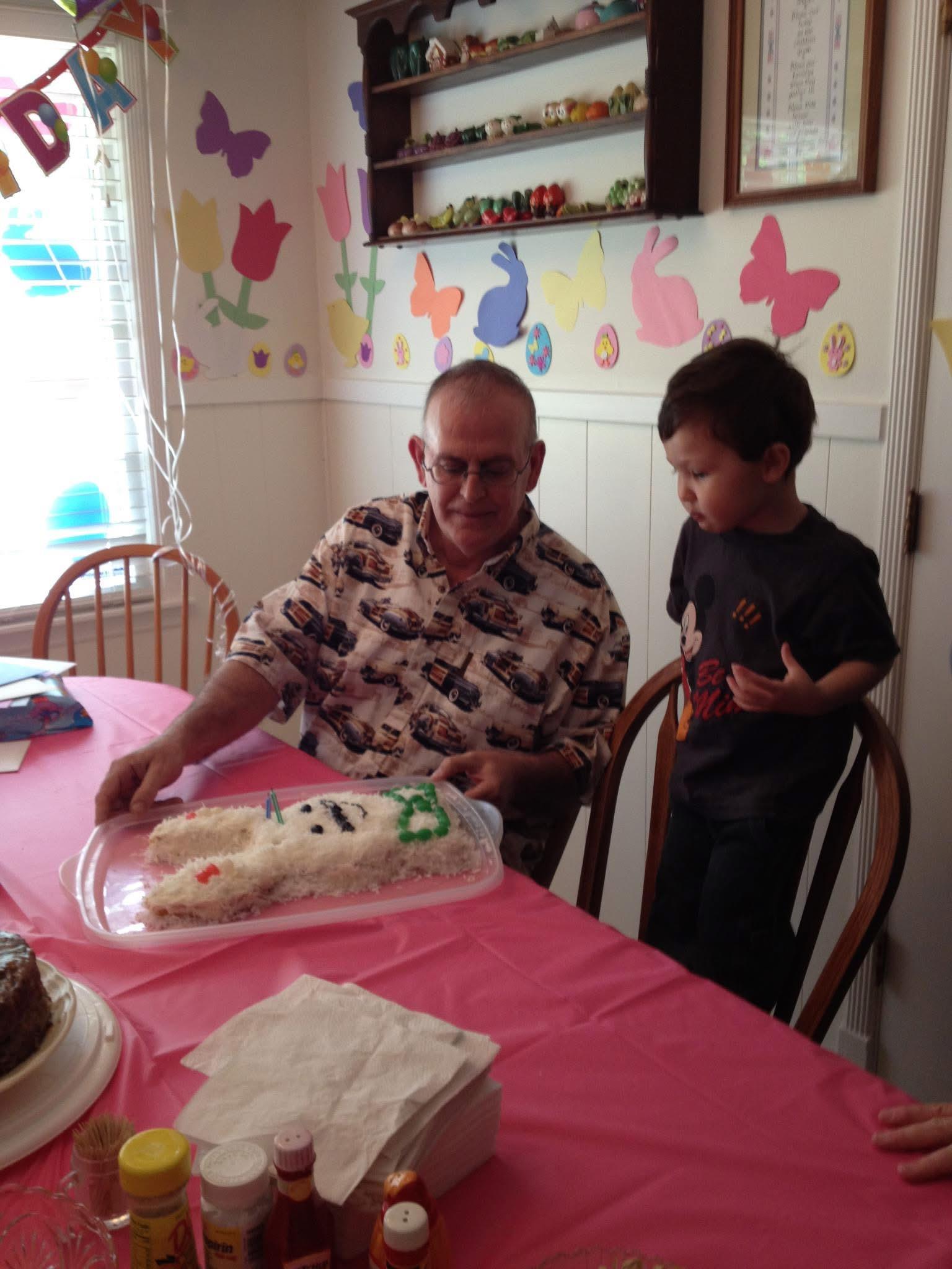 A grandfather and his young grandson enjoy a birthday cake together in a vibrant setting.