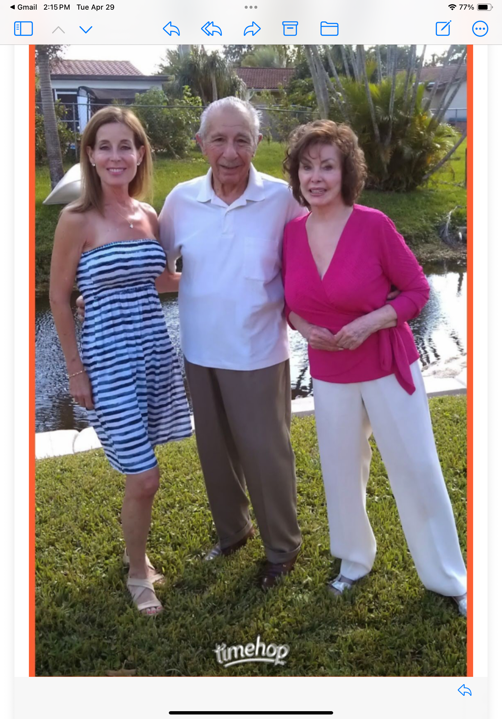 Three family members pose happily by a pond, enjoying a sunny day and each other's company.