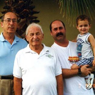 Family gathers in a backyard, showcasing four generations with warm smiles and a playful atmosphere.