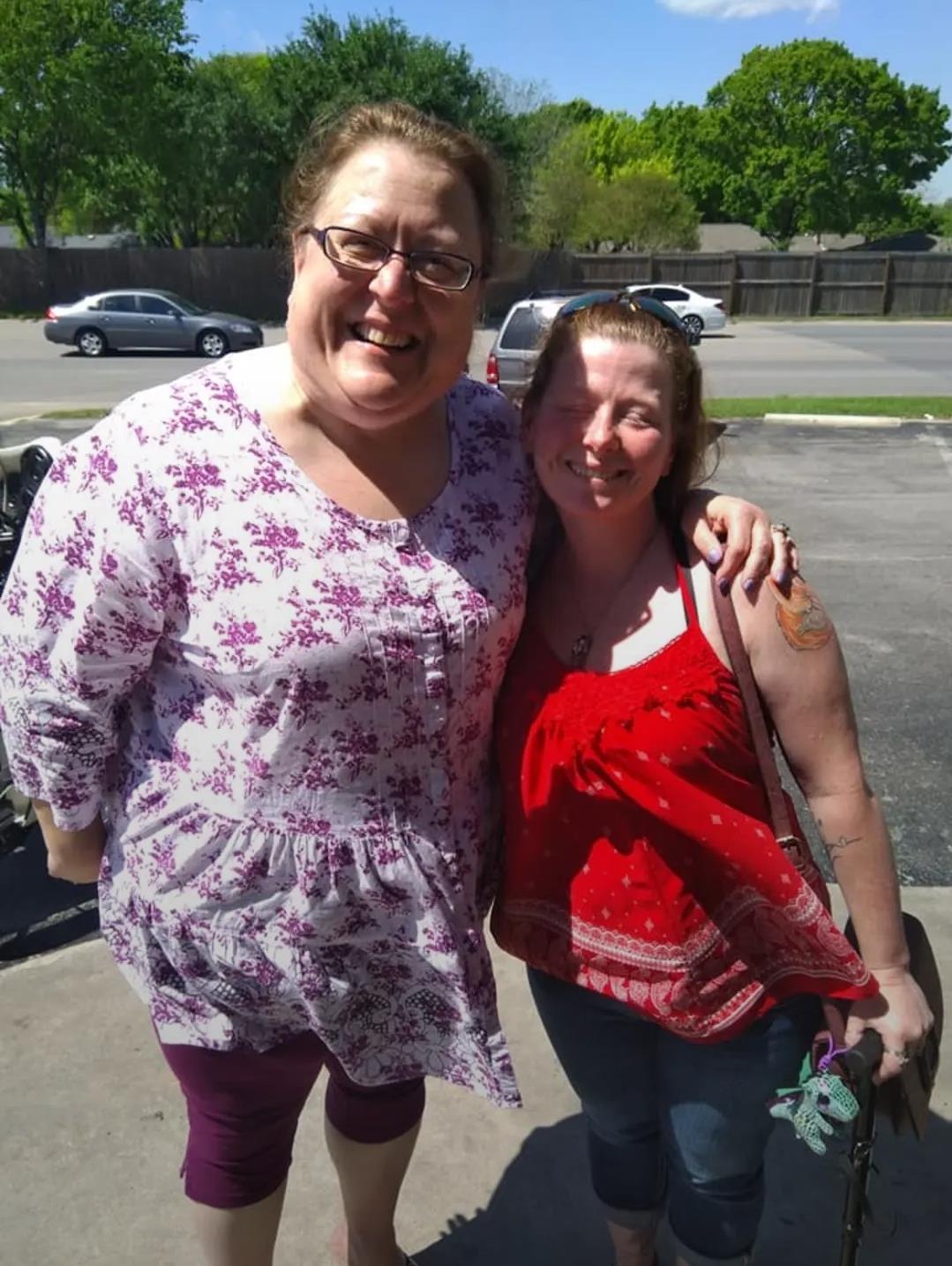 Two women share a happy moment outside, enjoying their friendship on a bright day with clear skies.