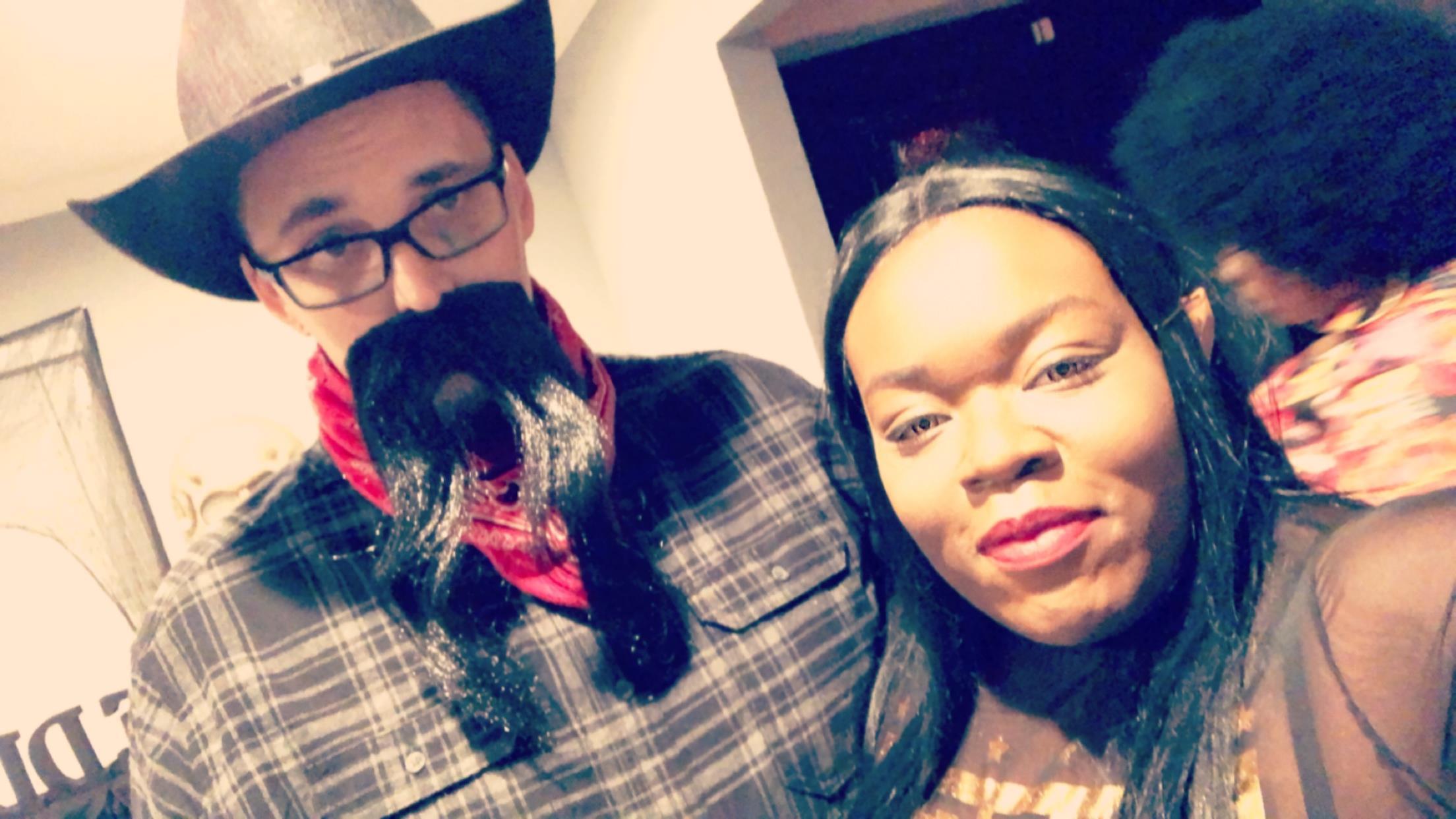 Two individuals dressed in costumes pose for a fun moment during a festive gathering.