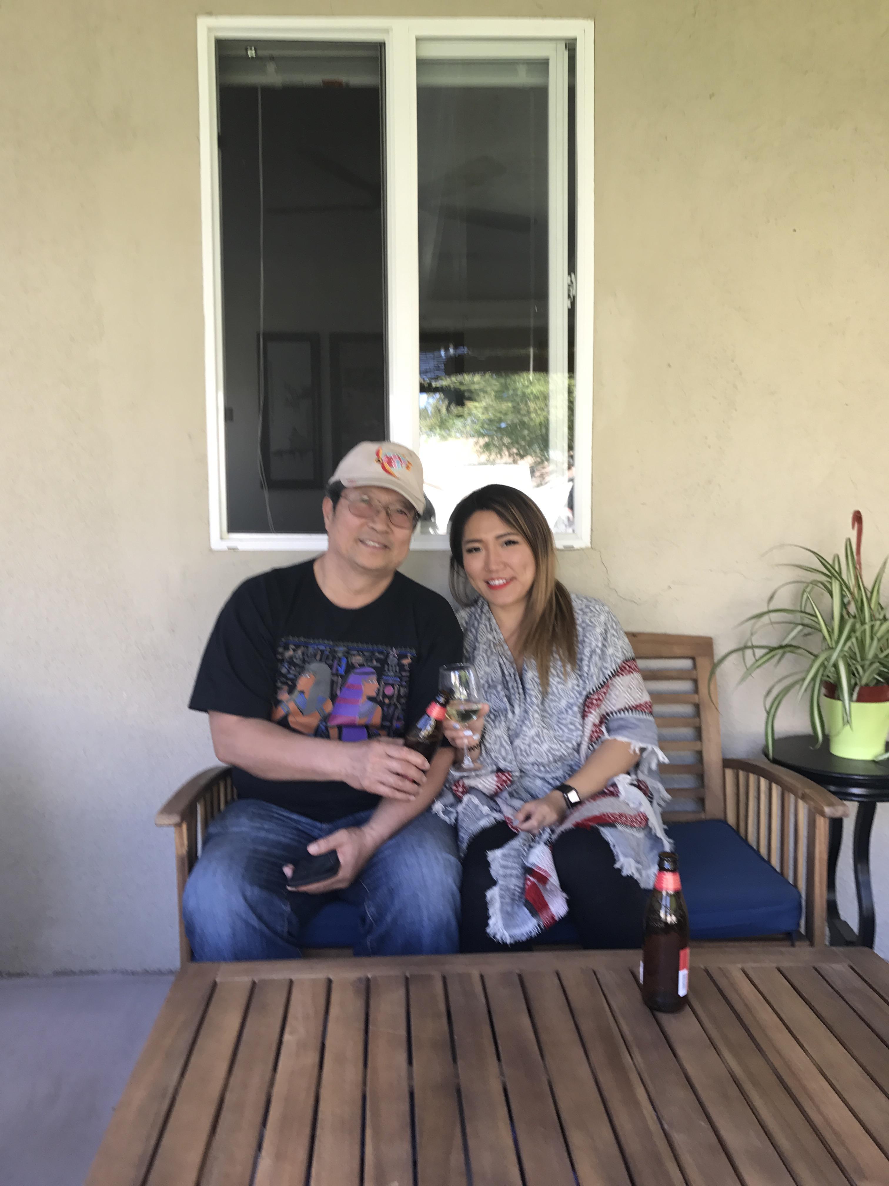 Two people relax on a wooden bench, sipping beverages and enjoying each other's company.