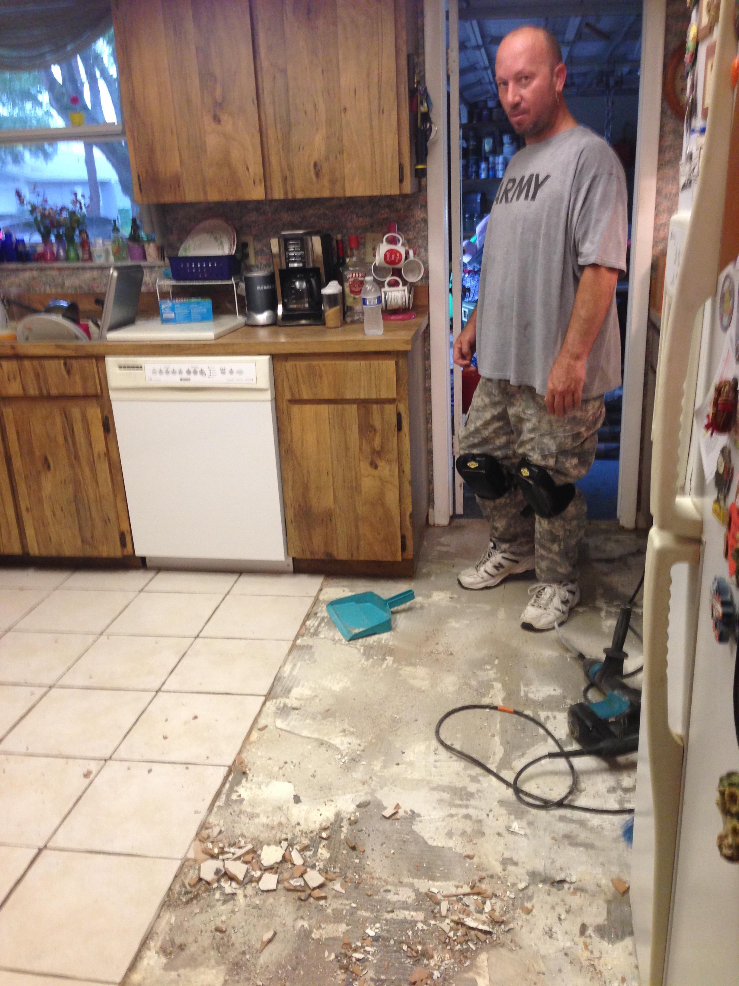 A man is removing an old kitchen floor while preparing for a renovation project in this home.
