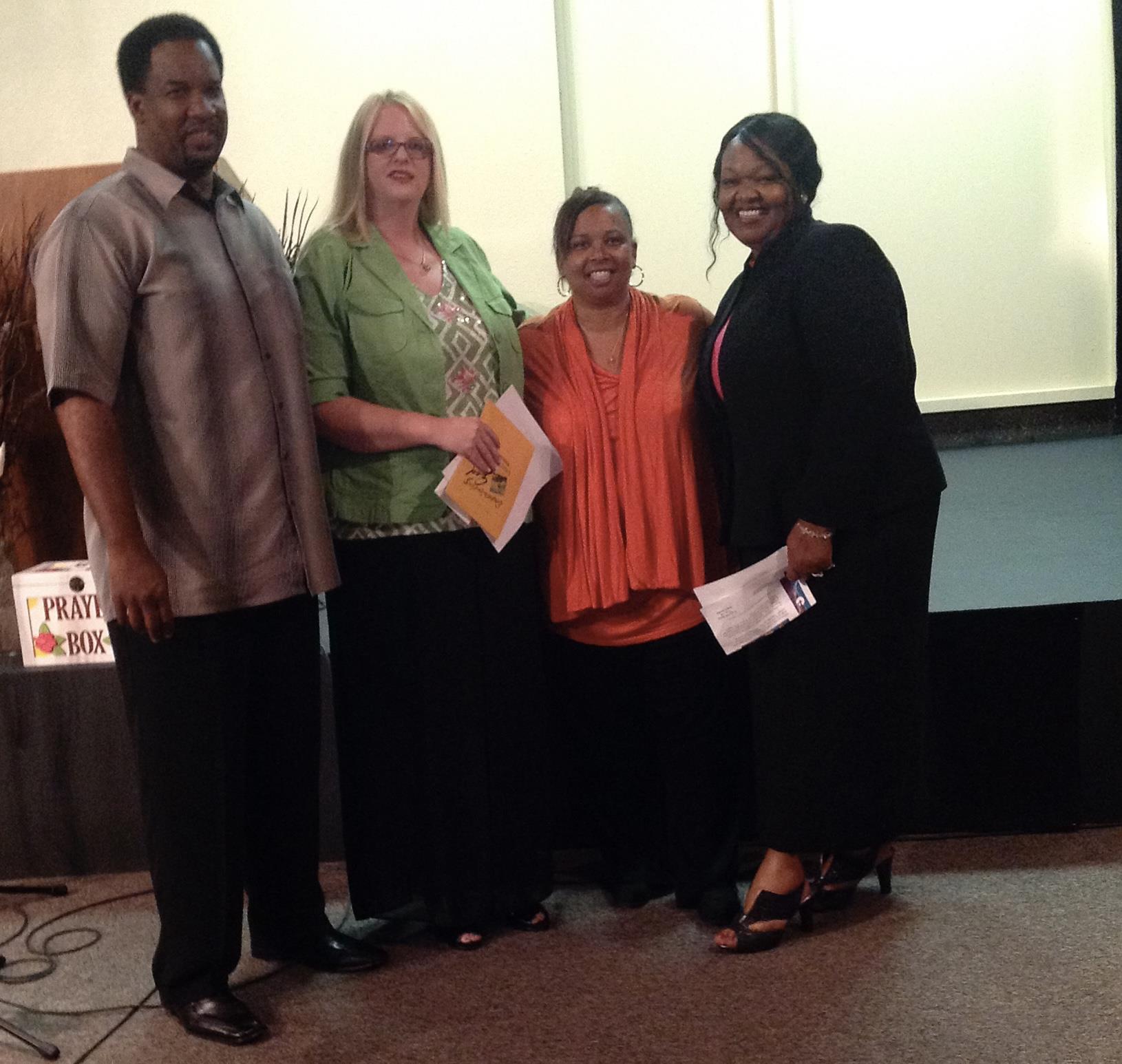 Four community leaders gather on stage, sharing smiles and celebrating accomplishments at an event.