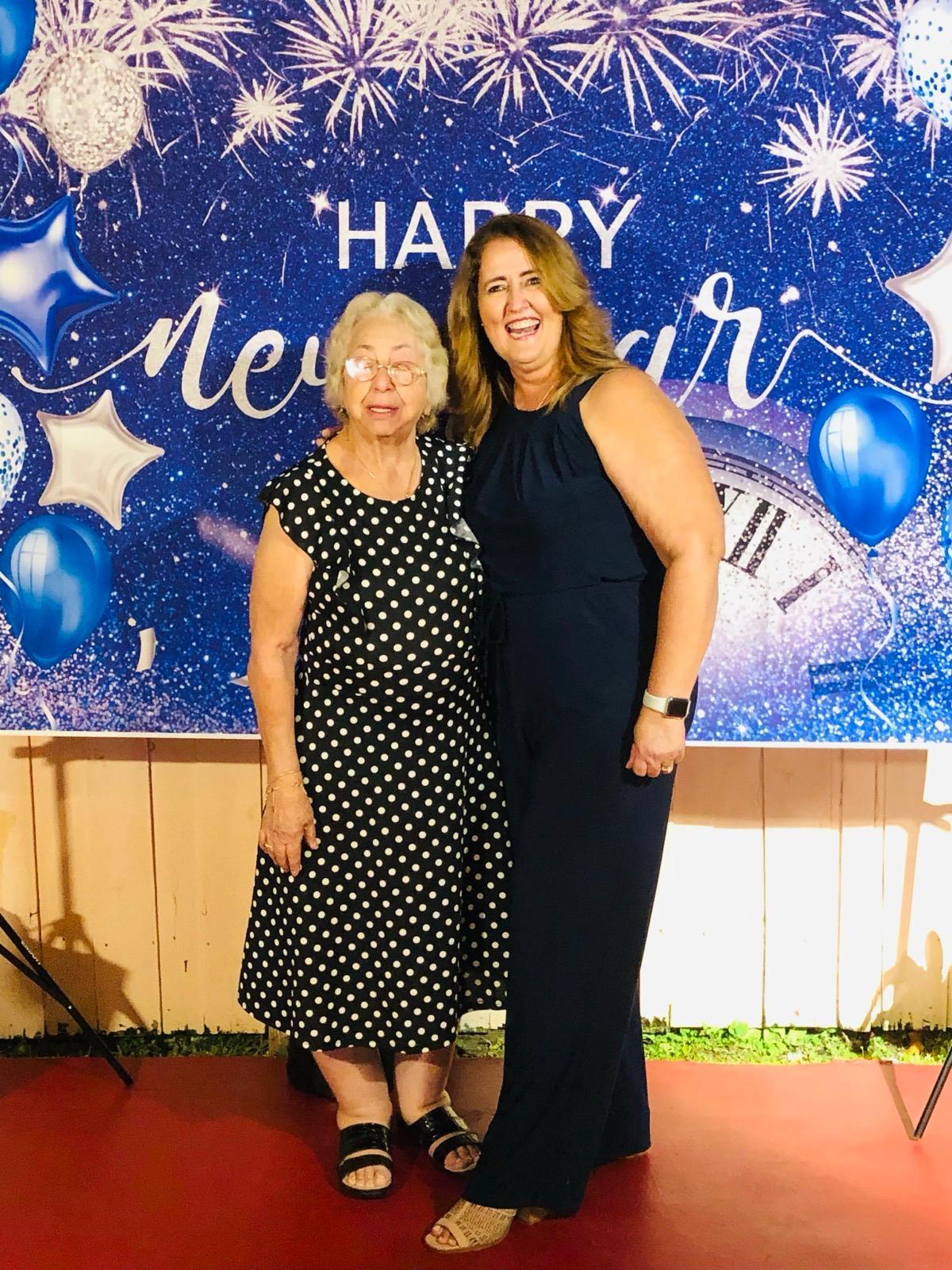 Two women happily celebrate New Year's Eve amidst festive balloons and stars.