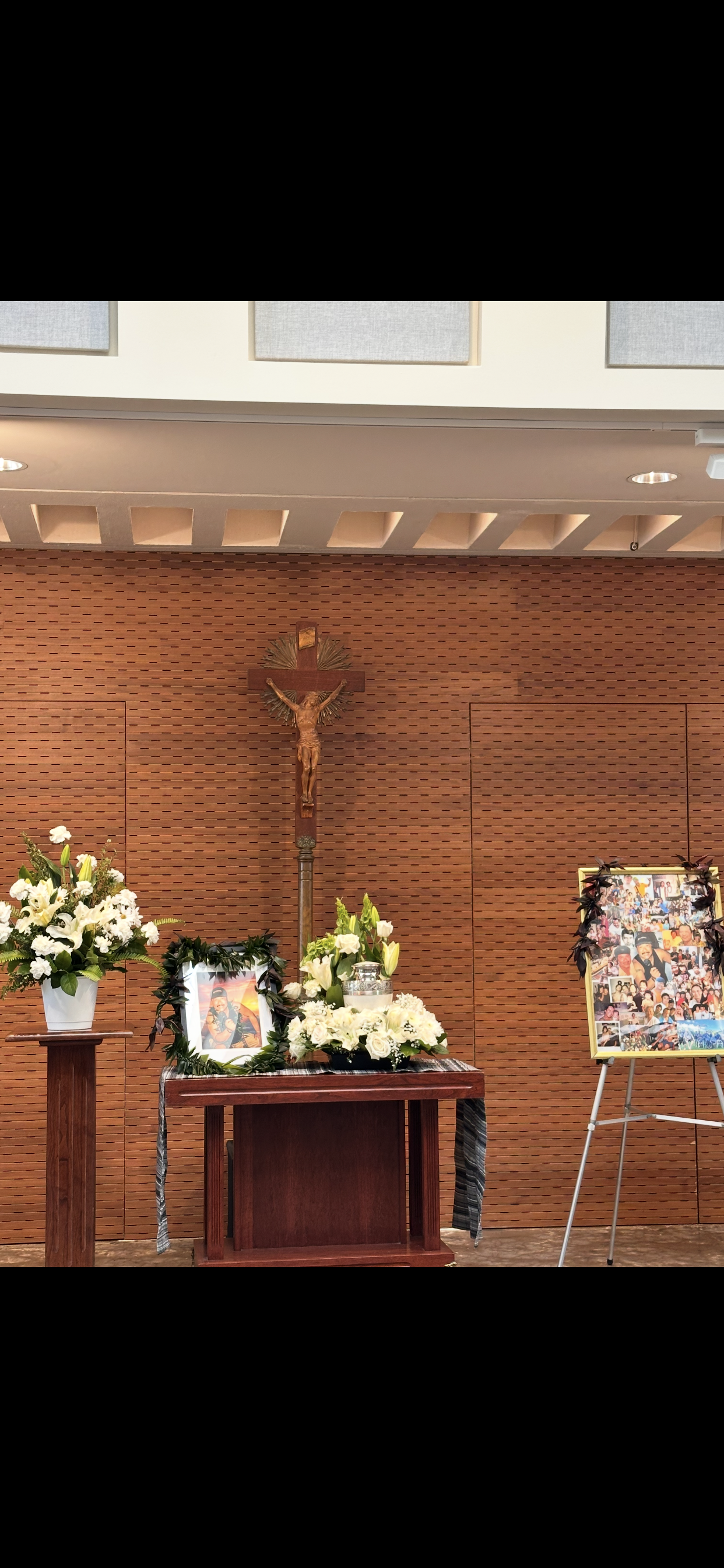A touching memorial features flowers, a cross, and portraits reflecting cherished memories.