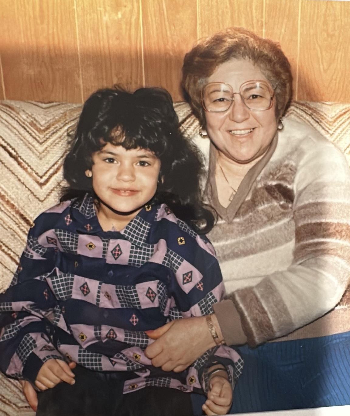 A smiling grandmother and granddaughter enjoy a warm moment together in their living room.