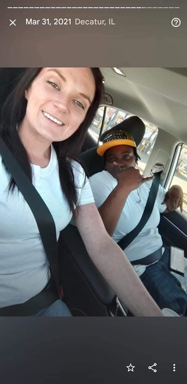 Two friends are happily taking selfies in a car with smiles and joyful expressions.