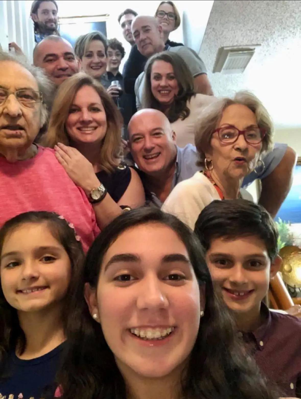 Group of family members smiling together in a staircase, enjoying a warm reunion indoors.