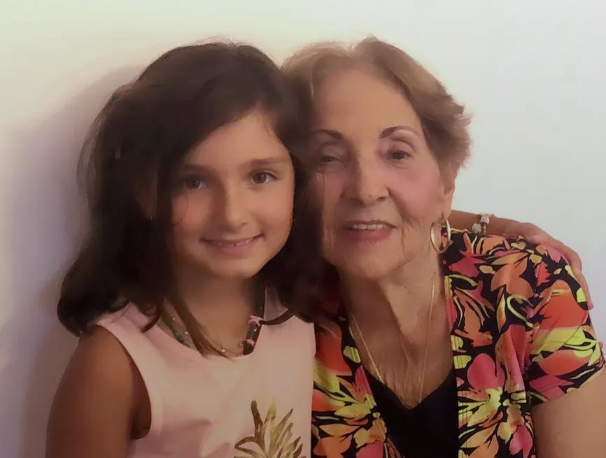 A joyful moment captured as a young girl embraces her grandmother, both smiling warmly.