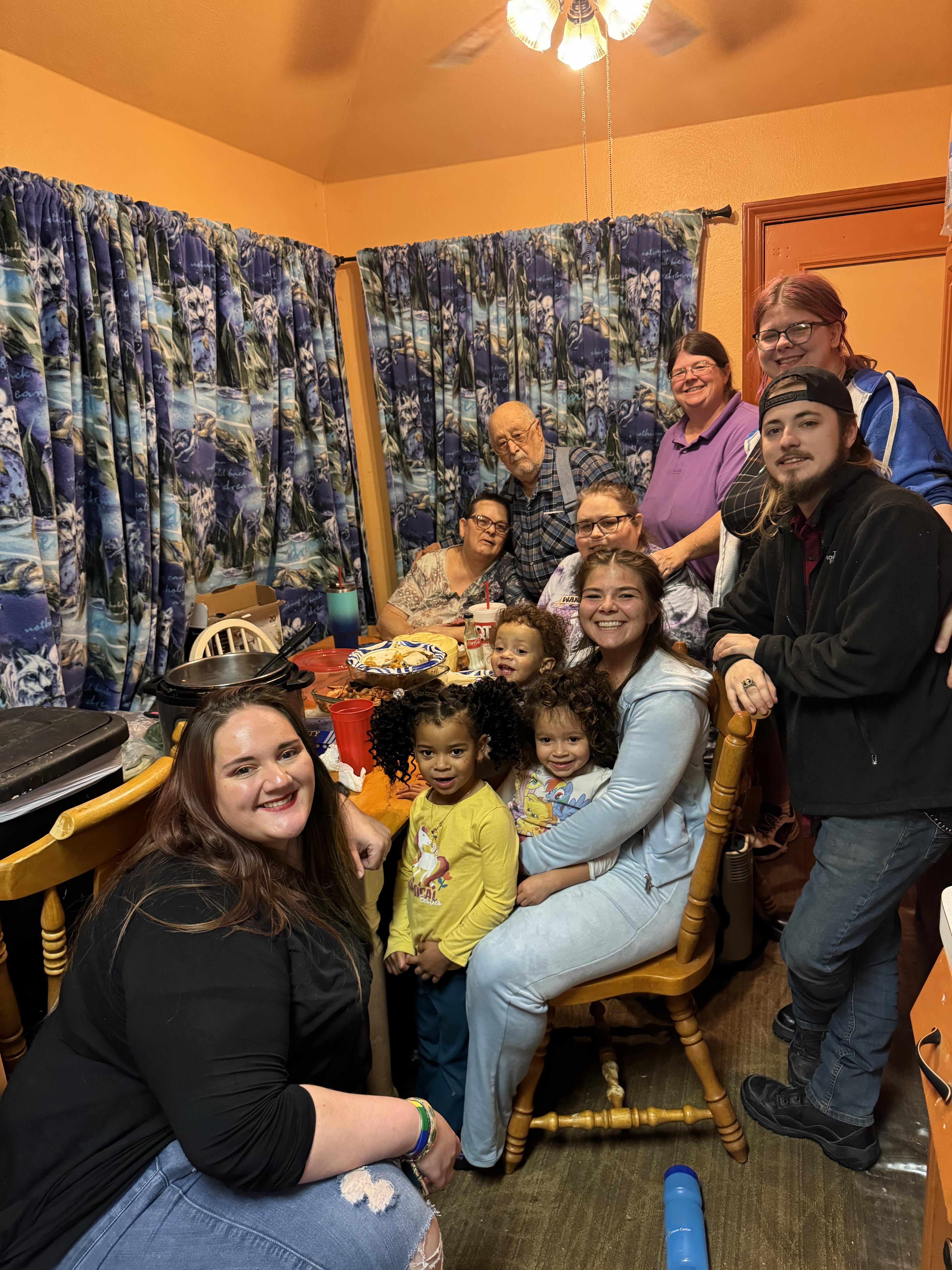 Family gathers around a table of delicious food in a lively kitchen.