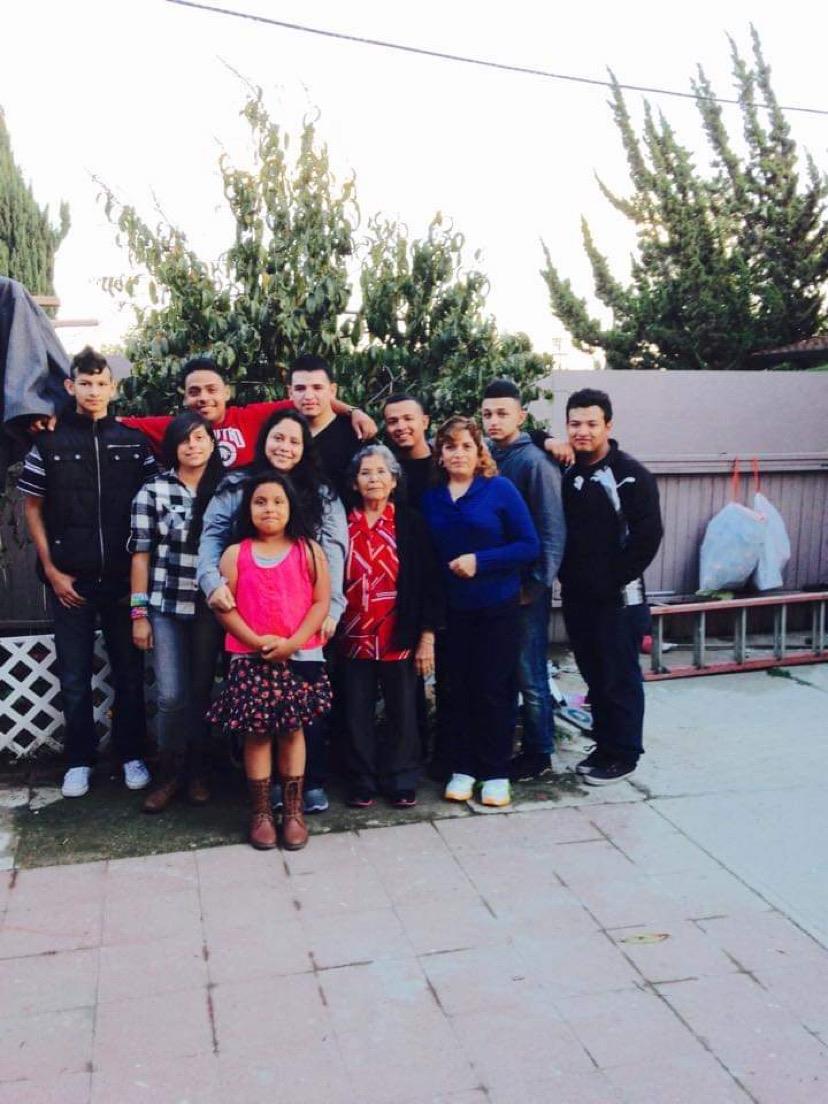 Relatives and children gather outside in a backyard for a fun family photo, smiling together.