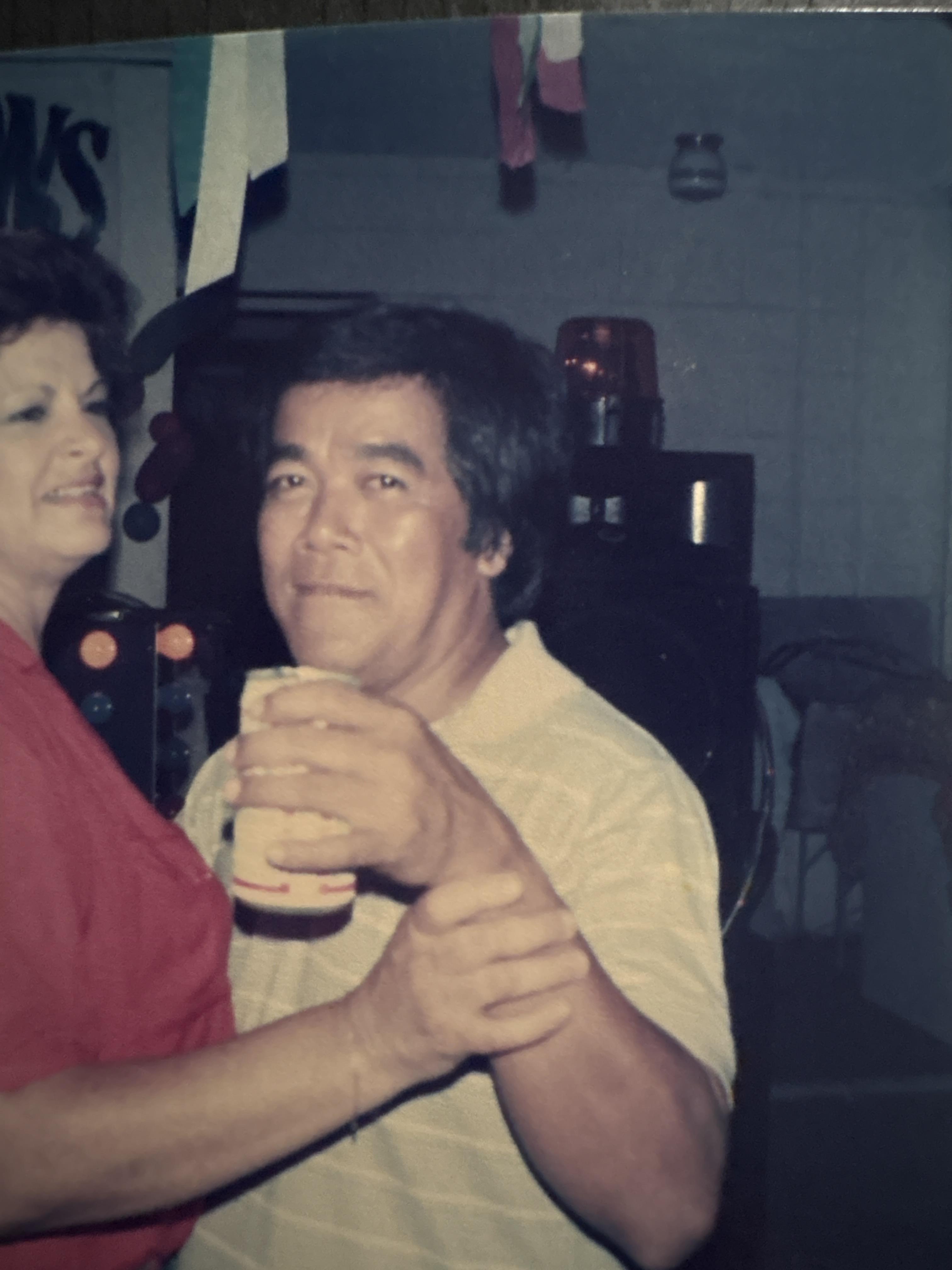 A couple dances closely, engaged in conversation while holding drinks at a festive gathering.