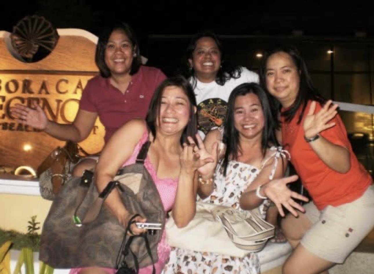 Group of friends posing happily together at night in Boracay, celebrating their vacation joyfully.