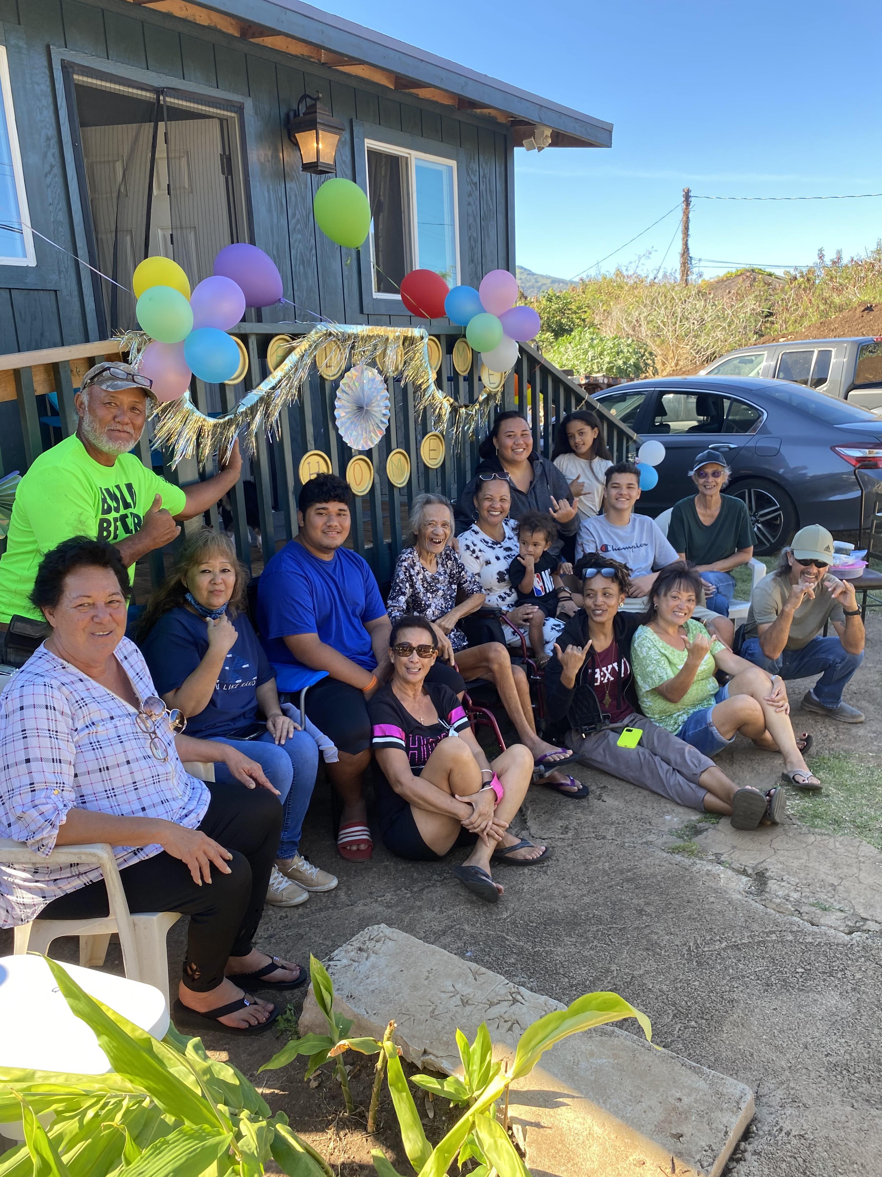 A joyful family gathers on the porch, celebrating a birthday with colorful balloons and smiles.