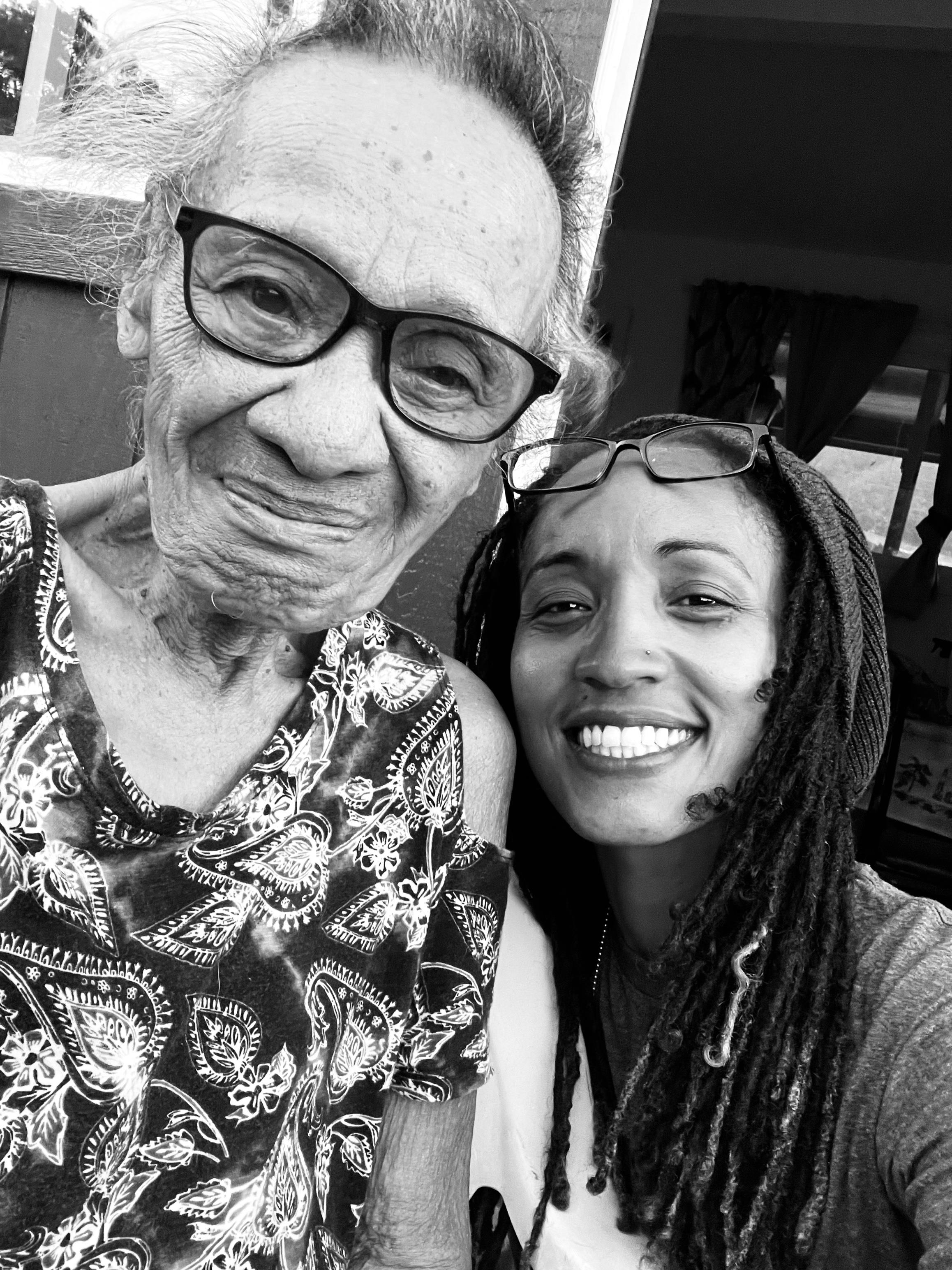 Two women smile together, showcasing their bond in a backyard on a bright day.