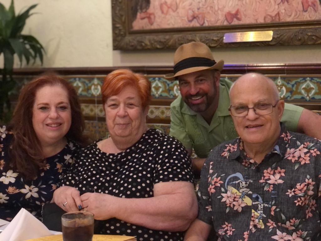 Four people enjoy a warm dinner together in a lively atmosphere, sharing smiles and conversation.