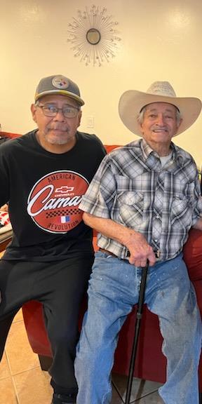 Two men share a joyful moment on a couch, surrounded by family warmth and love in a living room.