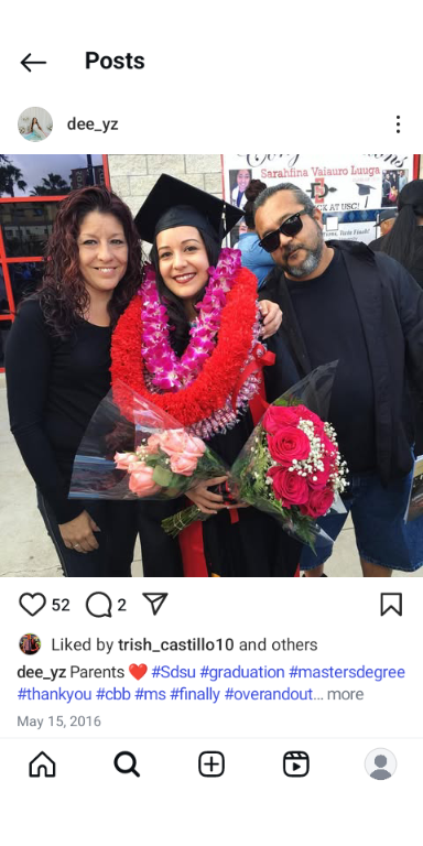 A graduate holds flowers while posing with her parents outside the university on graduation day.