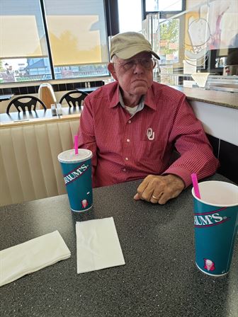 A man sitting at a table with two cups of soda