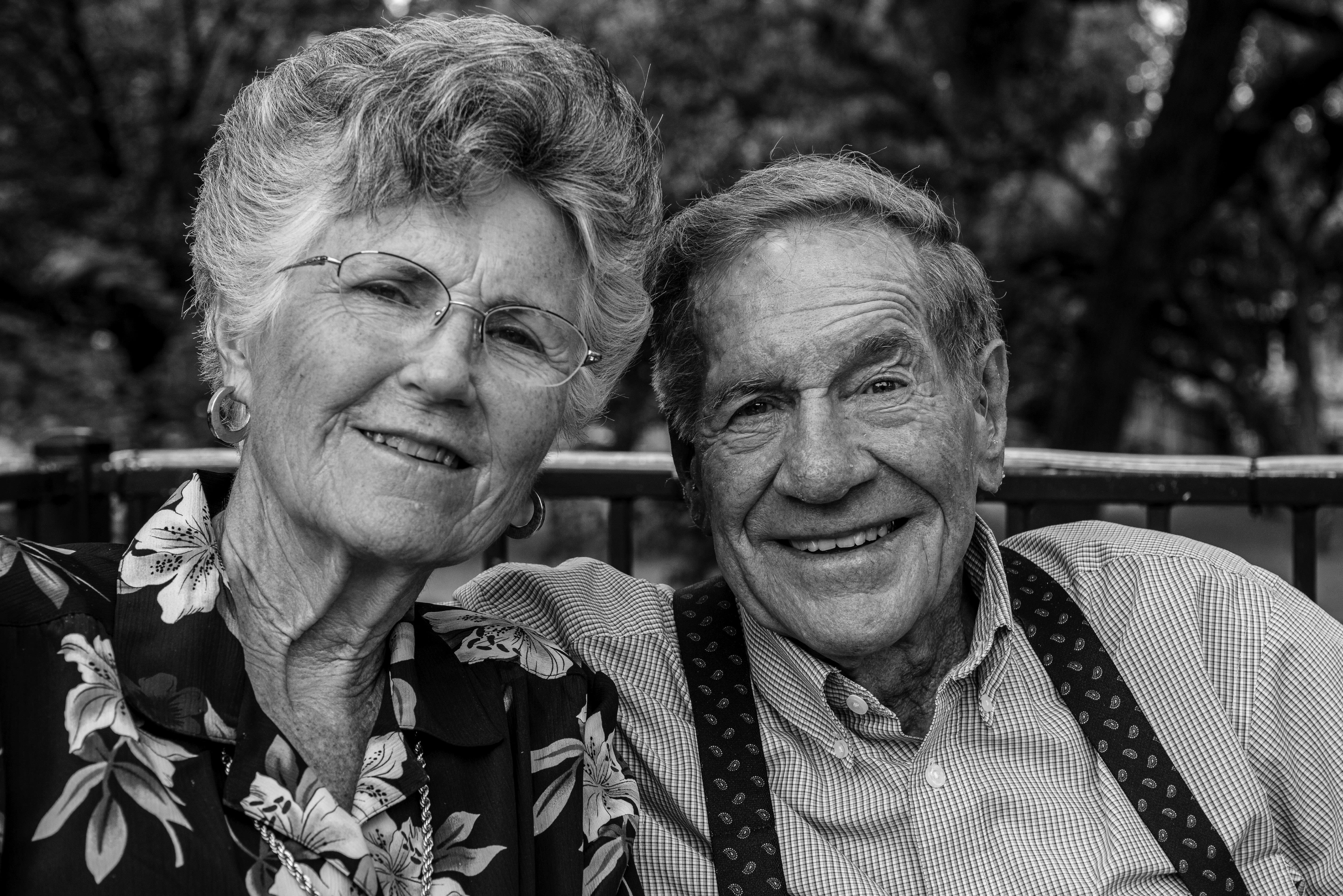 Elderly couple enjoys a joyful moment together in a park, sharing smiles and warmth.