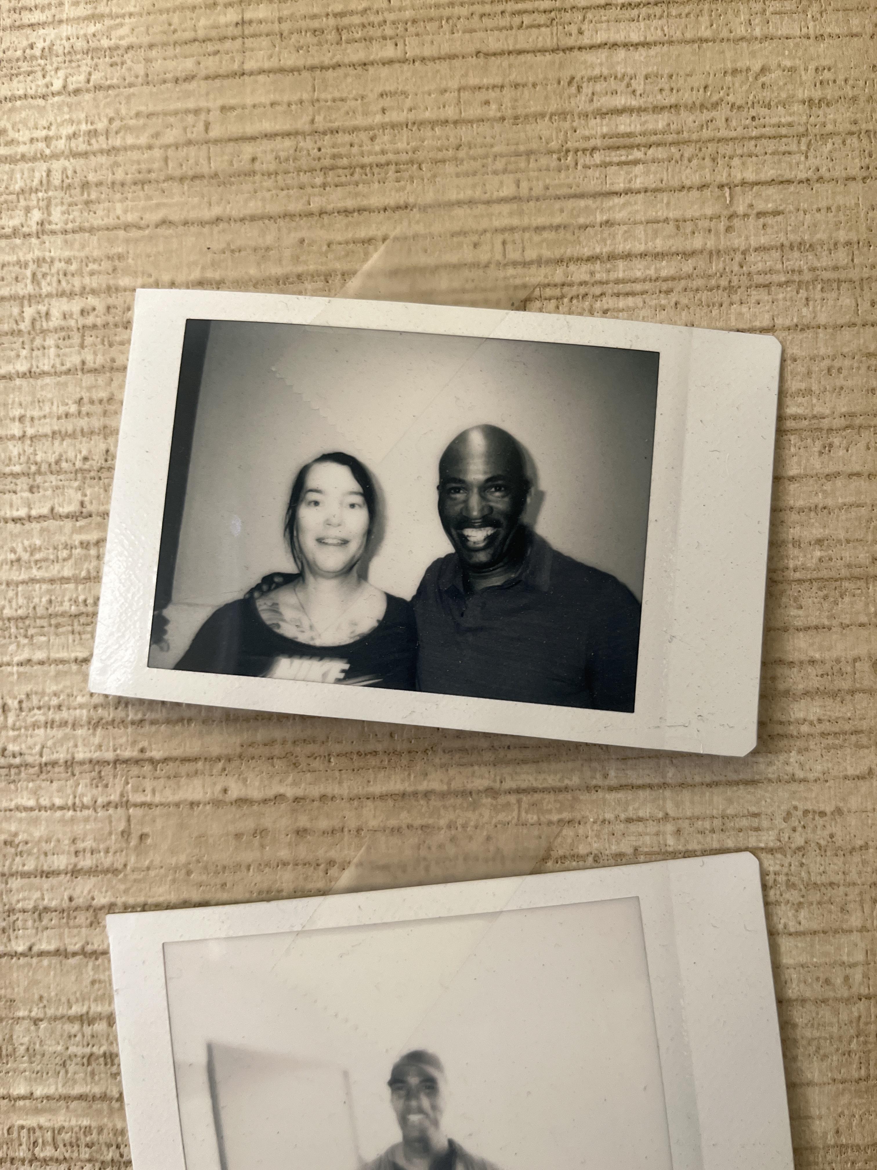 Two individuals pose happily together in a casual indoor setting, capturing a joyful moment.