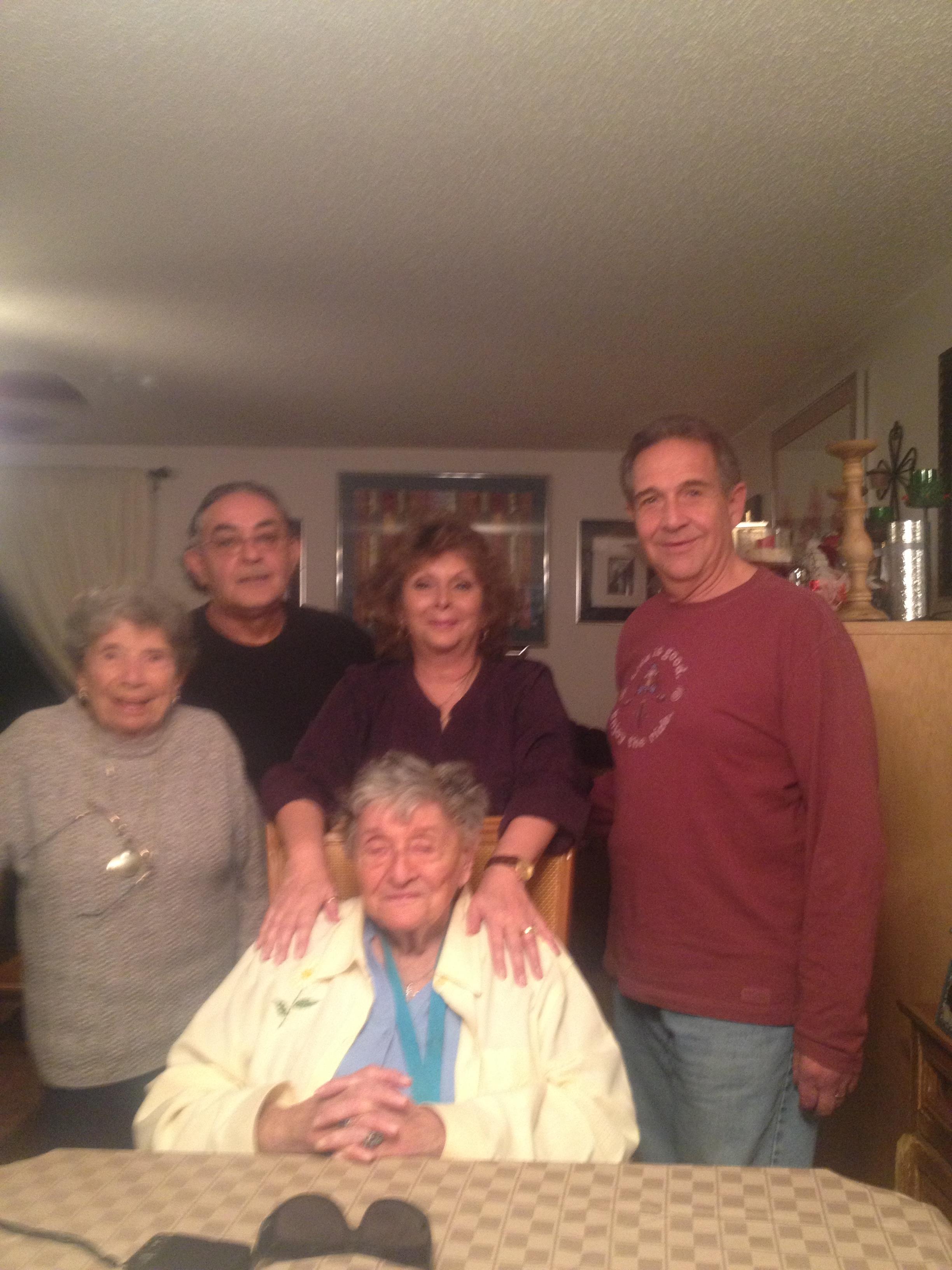 Five family members pose together in a warm, inviting living room during a joyful gathering.