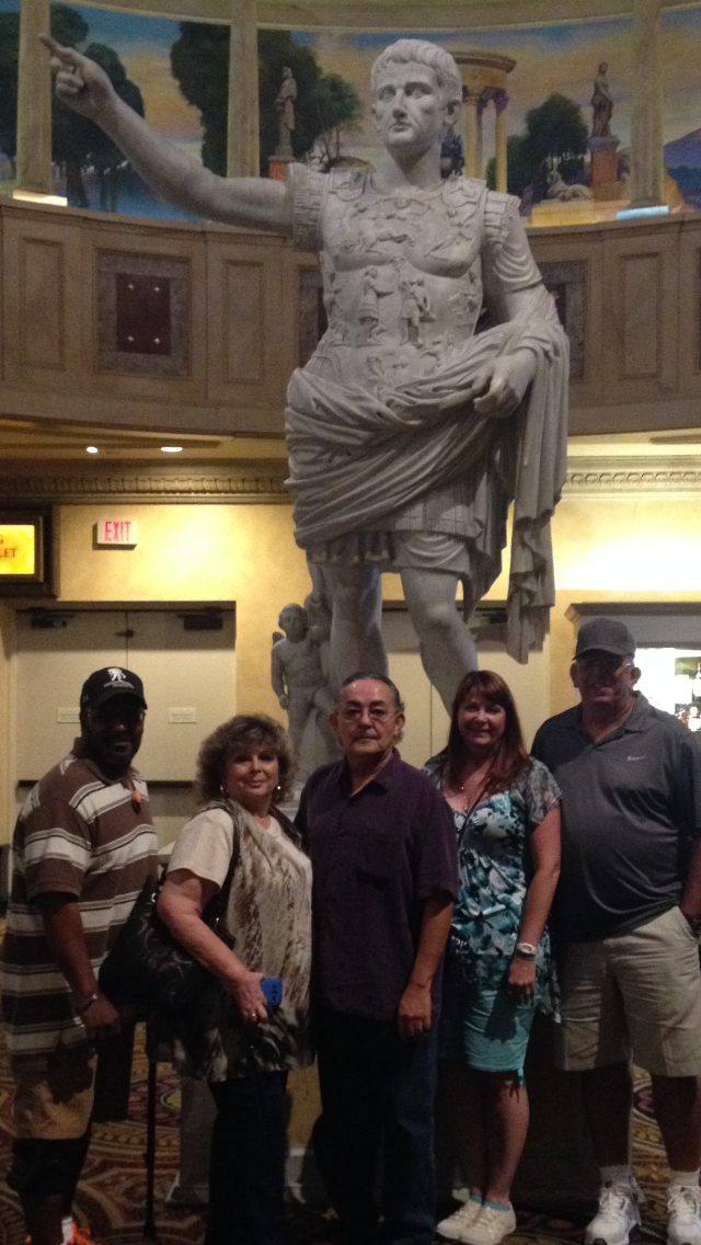 Friends gather around a grand statue, enjoying their time at a cultural exhibition in the evening.