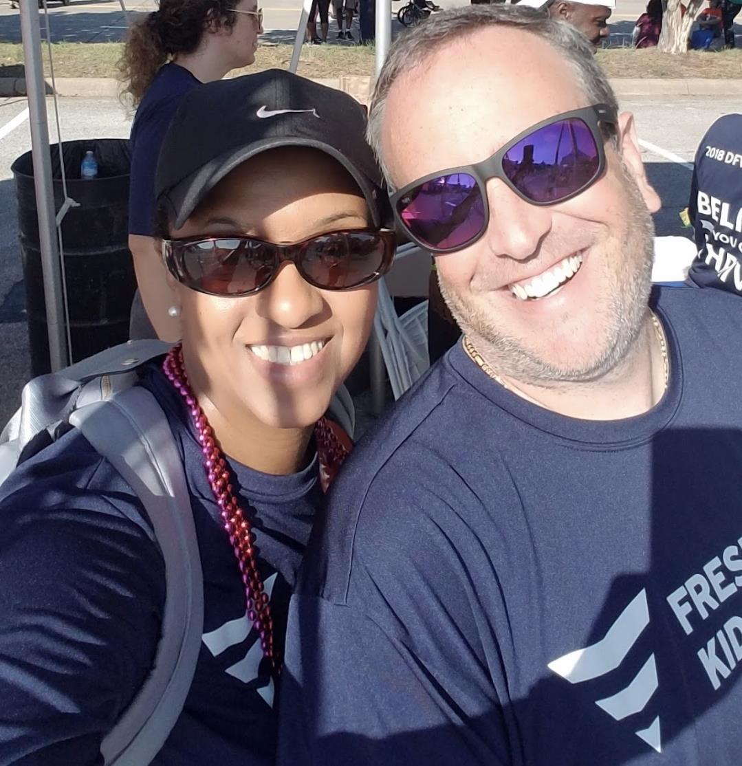 Two smiling individuals pose together at a community event, showcasing their teamwork and joy.