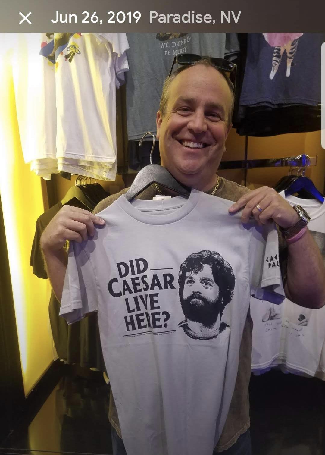 Man showcases a quirky t-shirt with a funny slogan in a shop in Paradise, Nevada.