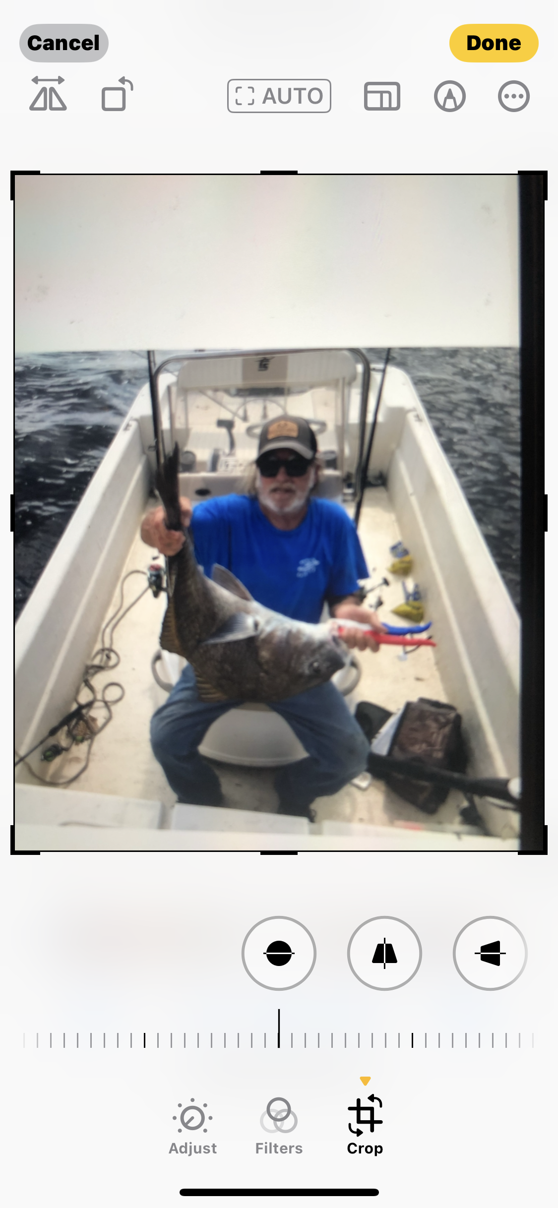 A man on a fishing boat proudly displays a large fish he caught.