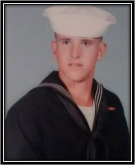 A young sailor stands confidently in uniform, displaying pride while facing the camera in a studio.