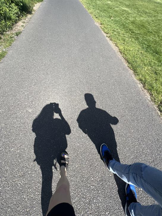 A shadow of two people on a road