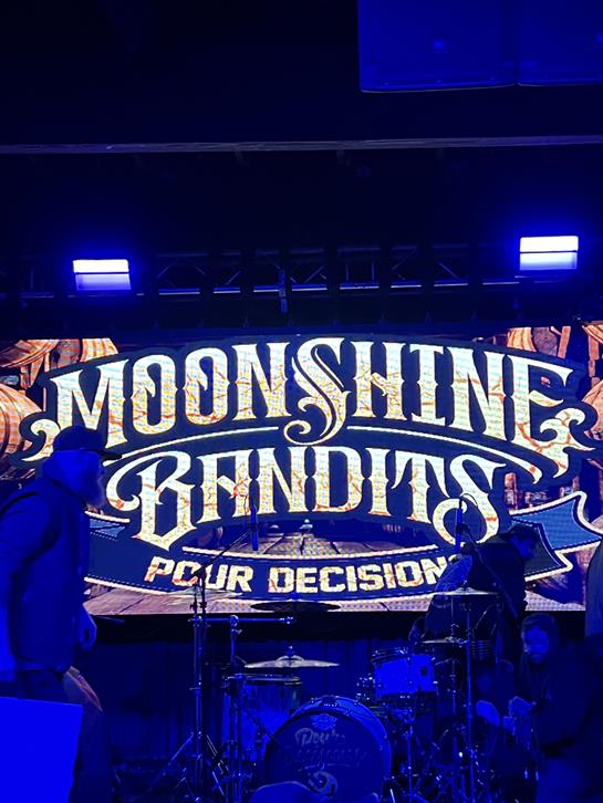 A band on stage with a sign