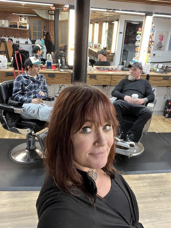 A woman taking a selfie in a barber shop